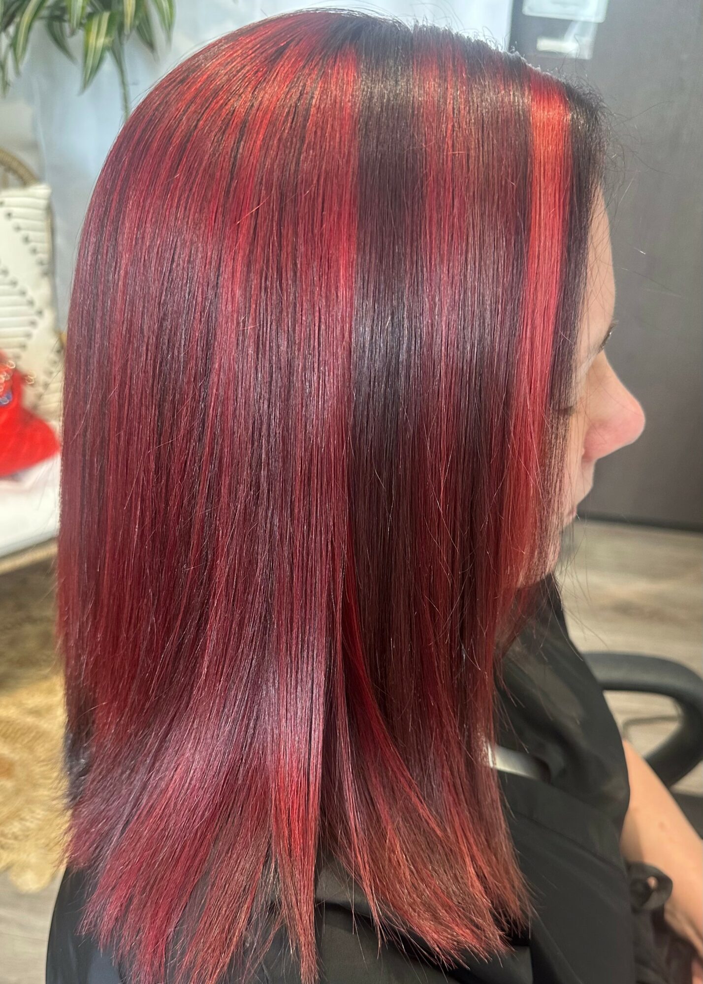 Side view of a woman with straight, shiny hair dyed in red and black shades.