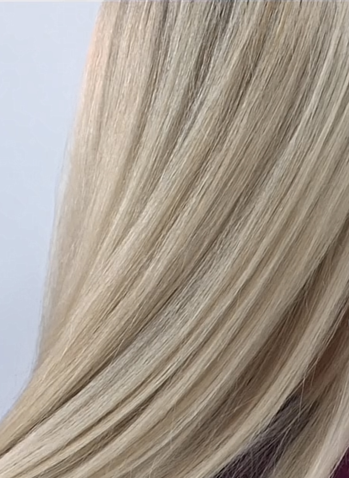 Close-up of straight, blonde hair with smooth texture and subtle highlights.
