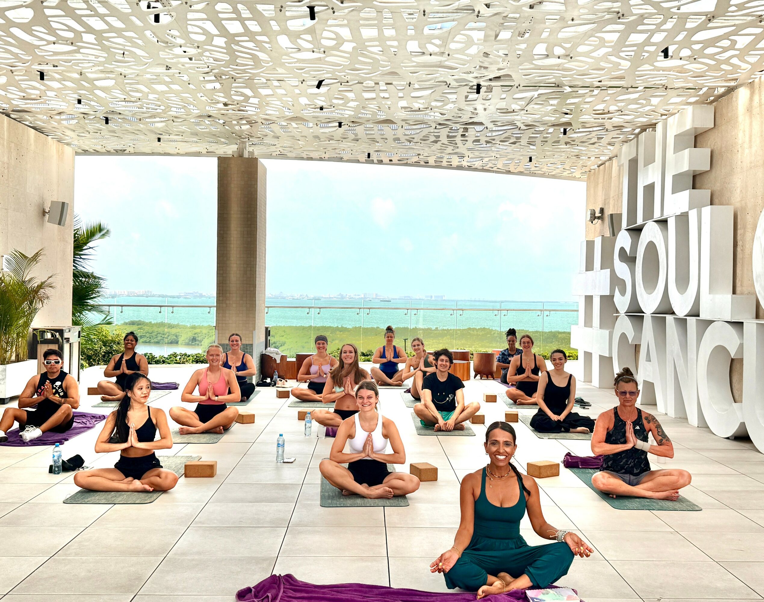 Group of people practicing yoga in a spacious indoor area with large windows and a view outside.