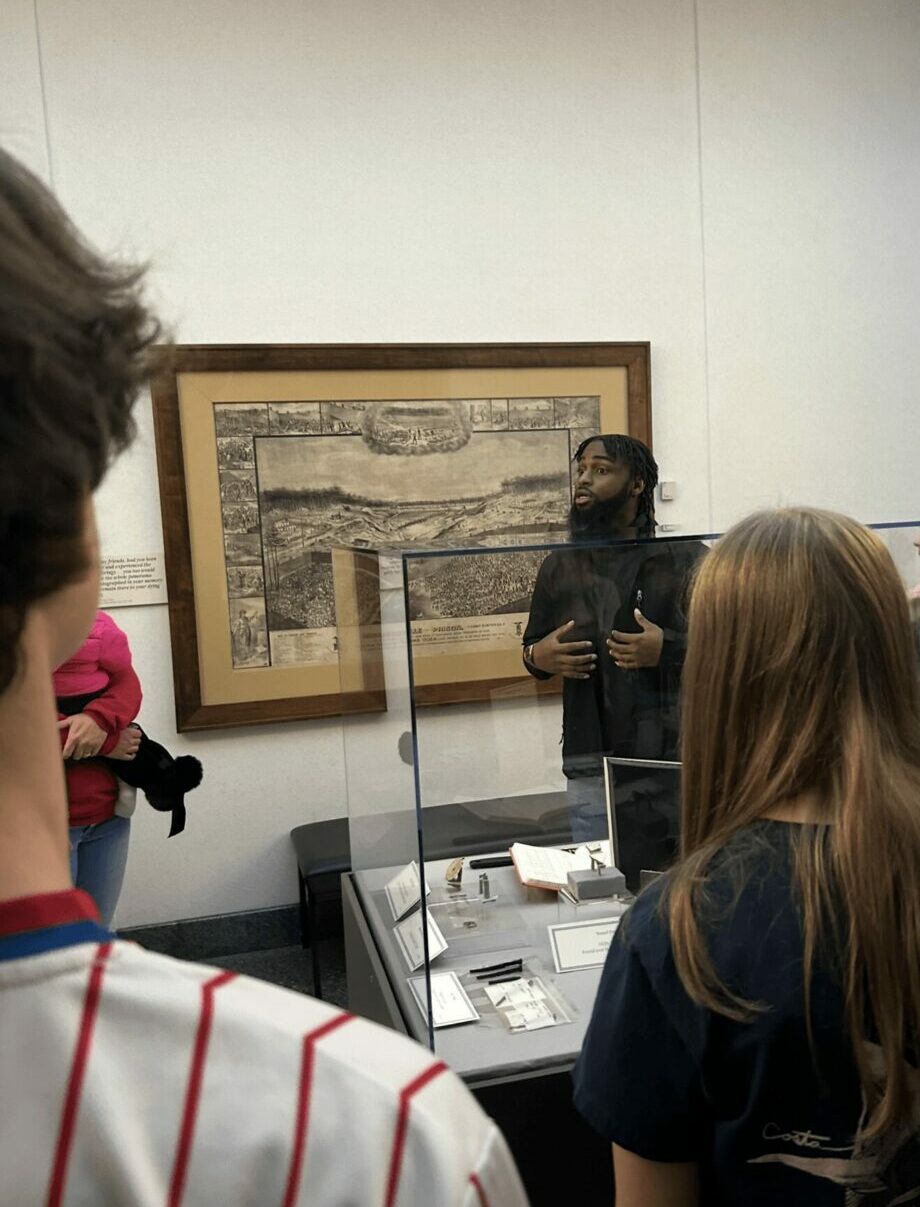 Group of people in a museum observing a framed artwork on the wall.