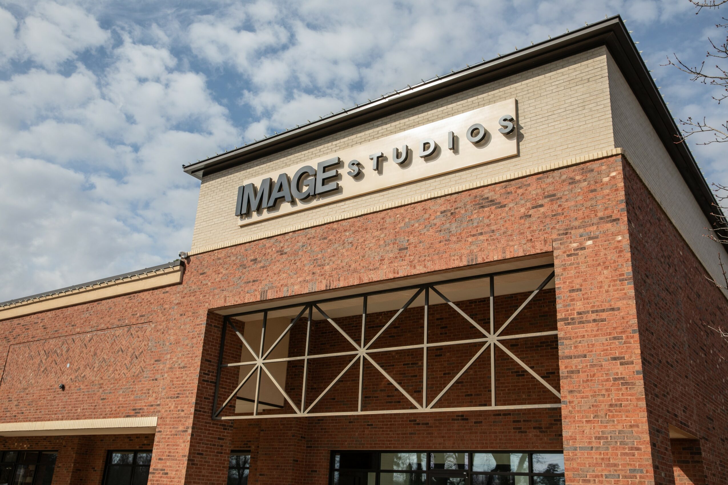 Brick building with a sign reading 'MAGE STUDIOS' on the upper part, under a partly cloudy sky.