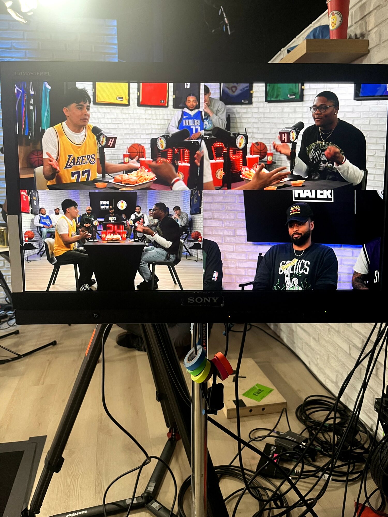 People sitting at tables in a room with screens on the wall, some eating and talking.