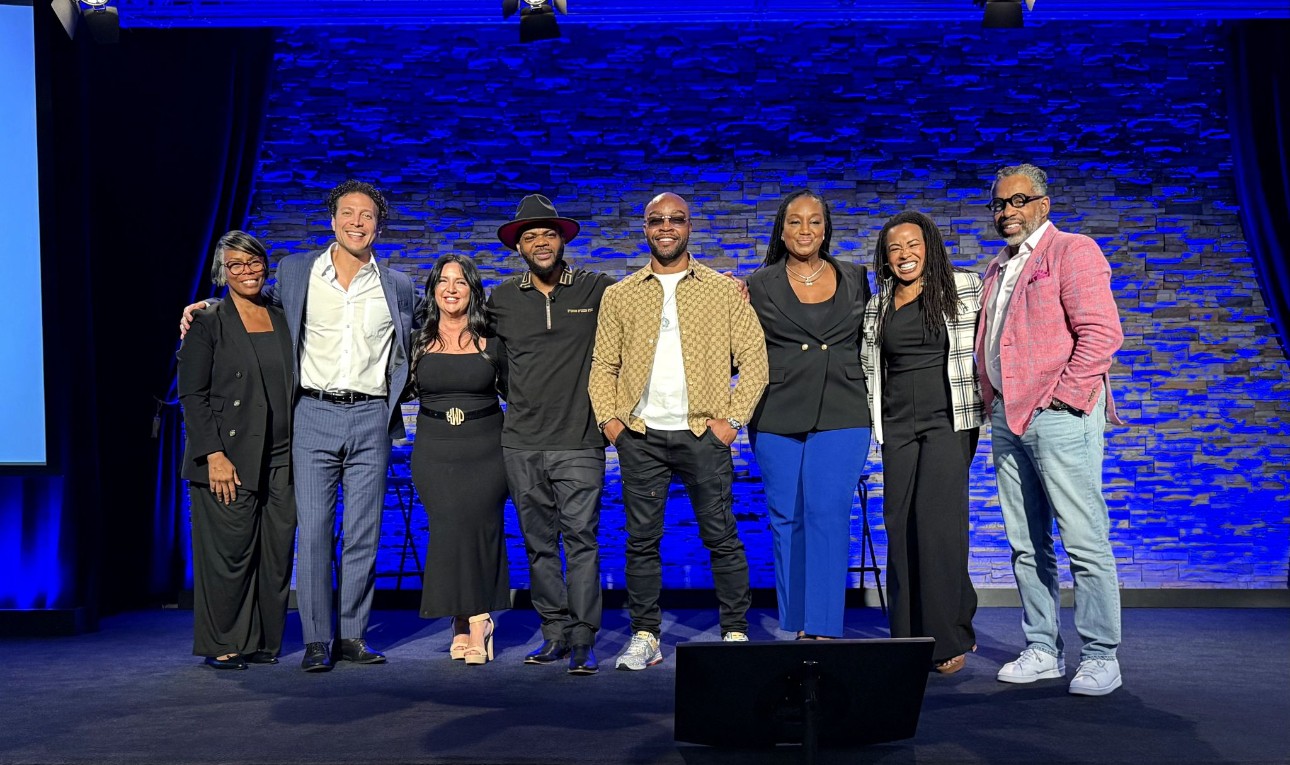 Group of eight people standing on stage with a blue textured background, smiling for a photo.
