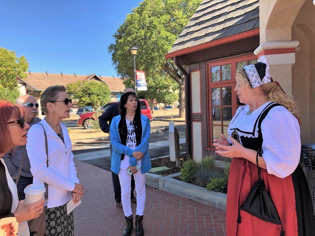 Nurse in uniform talking to a group of women on a sidewalk outside a building.