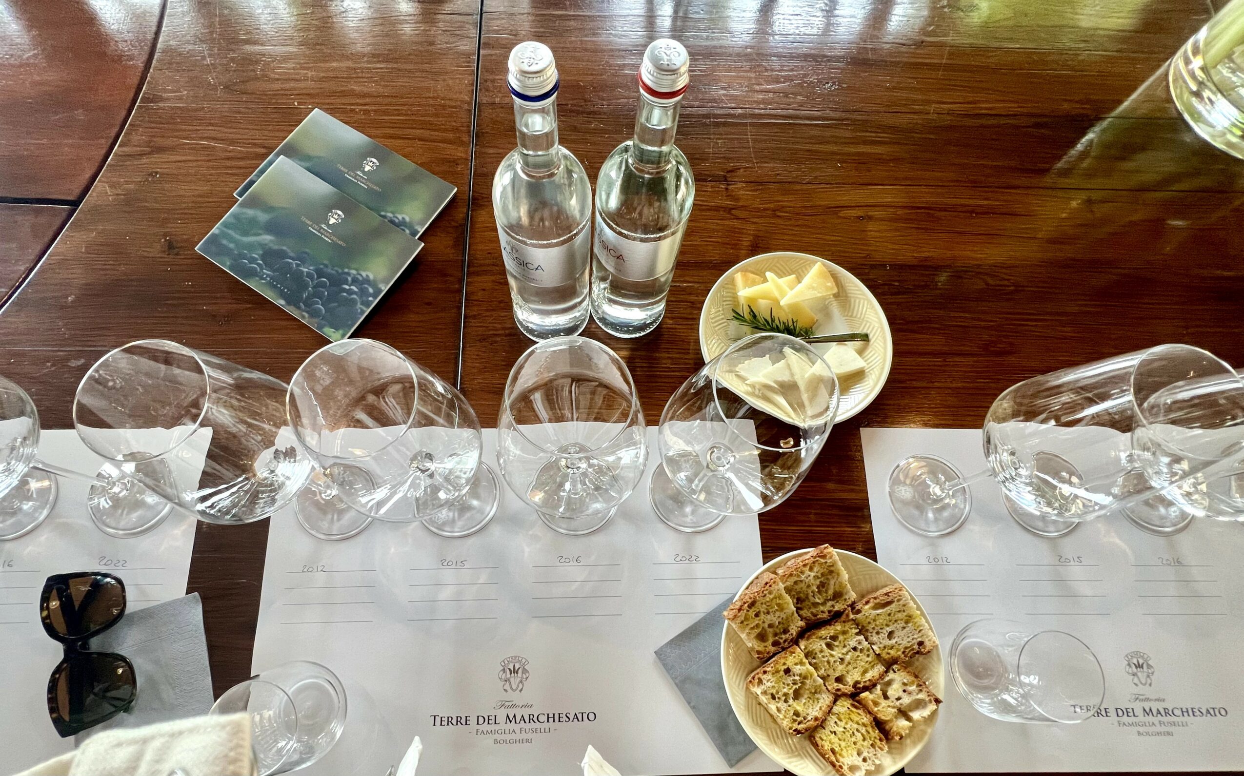 Table with empty glasses, bottled water, a plate with lemon slices, and a plate with sliced cake.