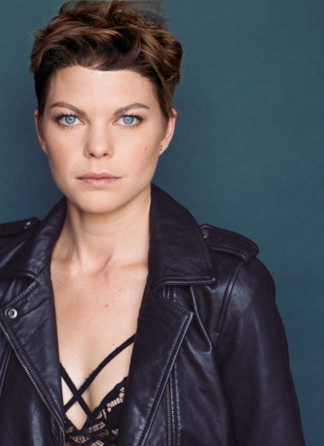 Woman with short hair wearing a black leather jacket against a dark background.