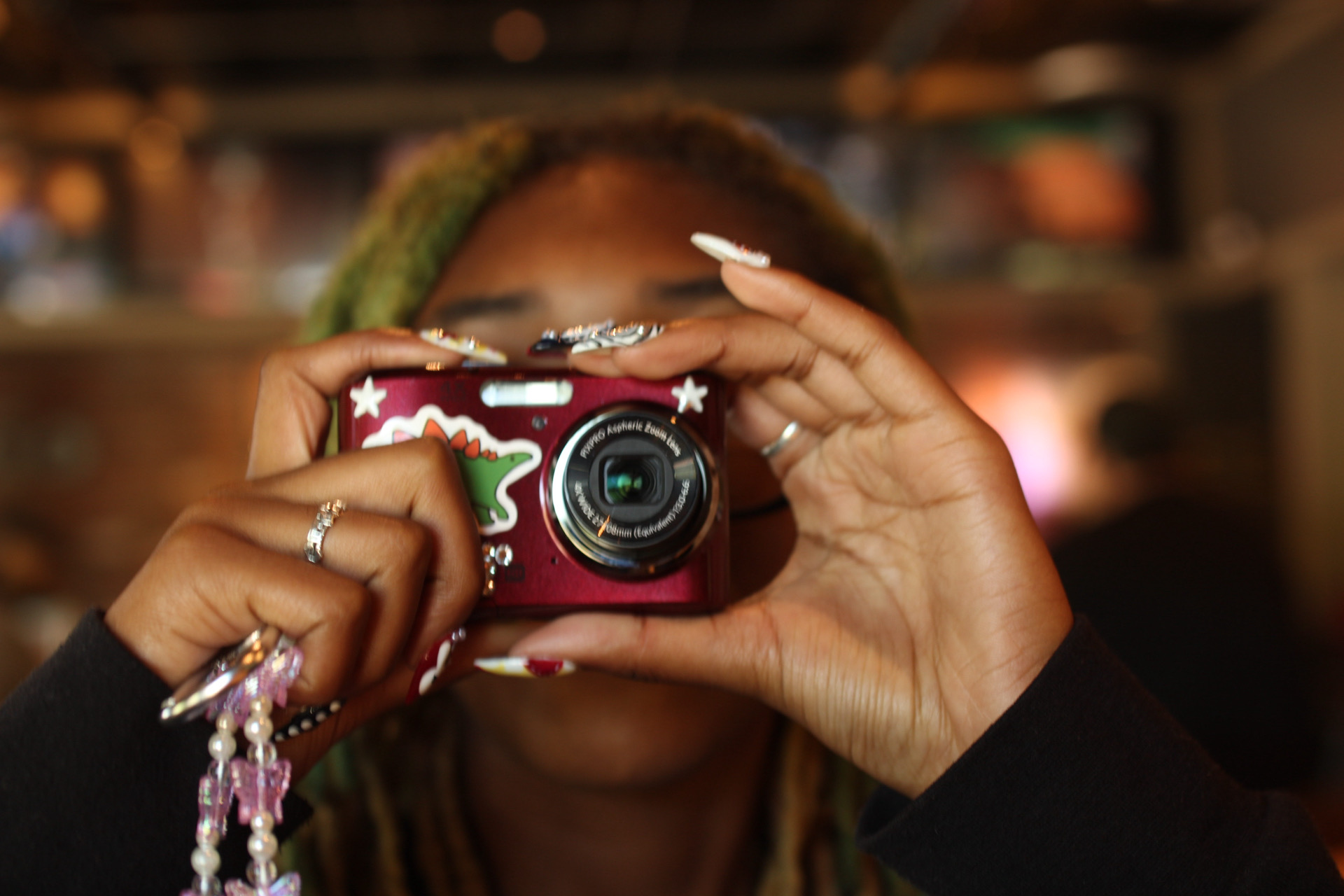 Person holding a red camera with both hands, taking a photo indoors.