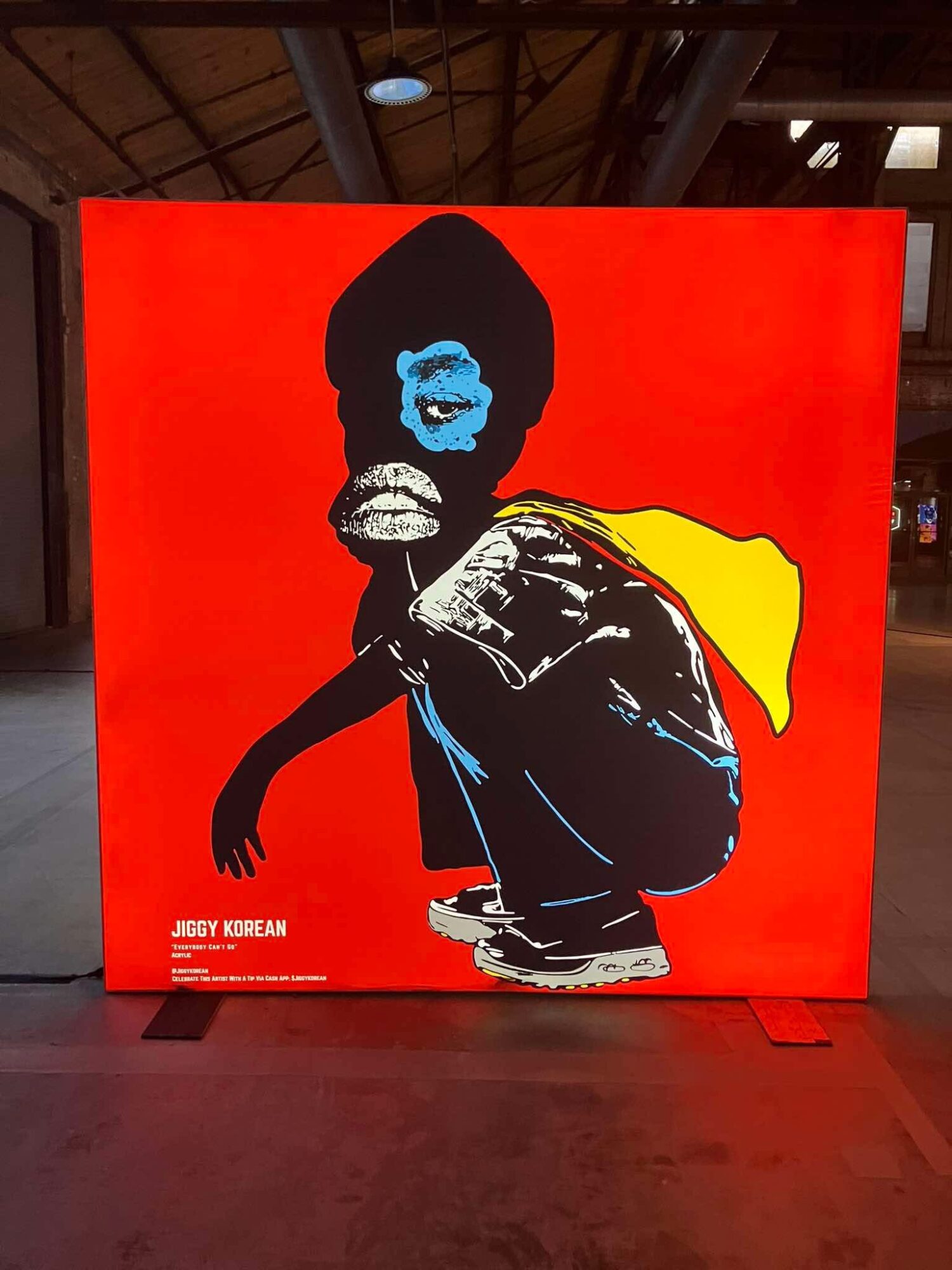 Artwork of a person with a blue face mask, yellow cape, and black clothing against a red background.