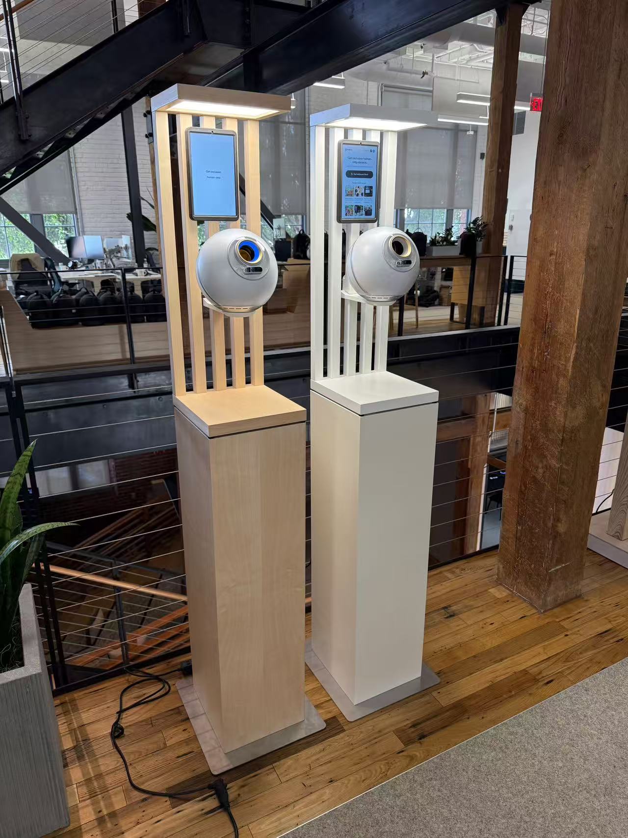 Two hand sanitizer dispensers on tall stands inside a building, with digital screens above the dispensers.