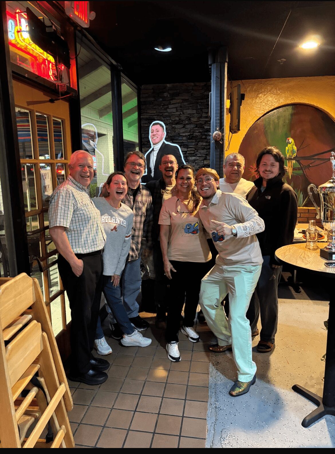 Group of seven people standing together in a restaurant or bar, smiling and posing for the photo.