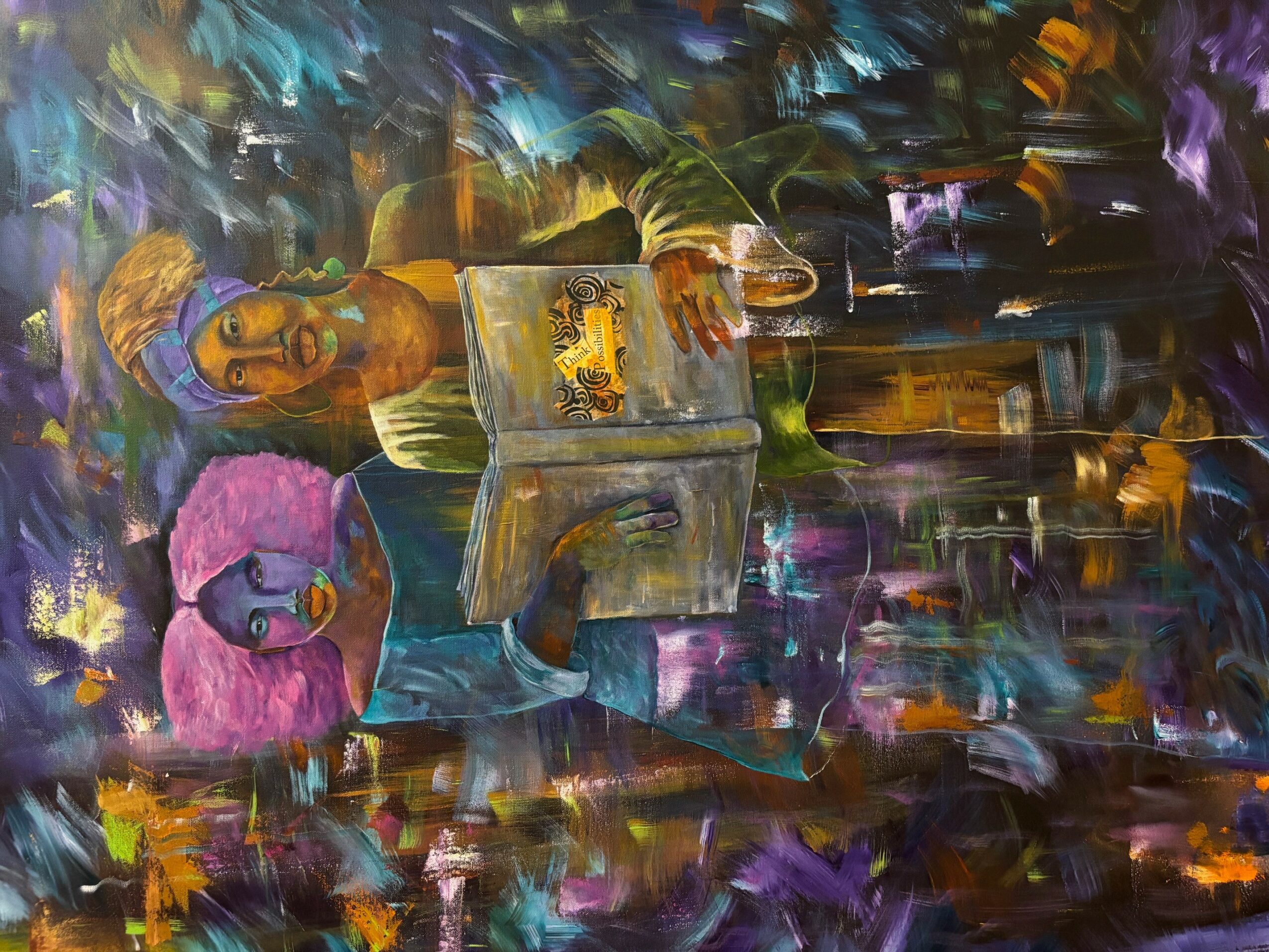 Person sitting at a table with a pink fluffy object, surrounded by colorful abstract background, holding a glass, with a laptop and food on table.