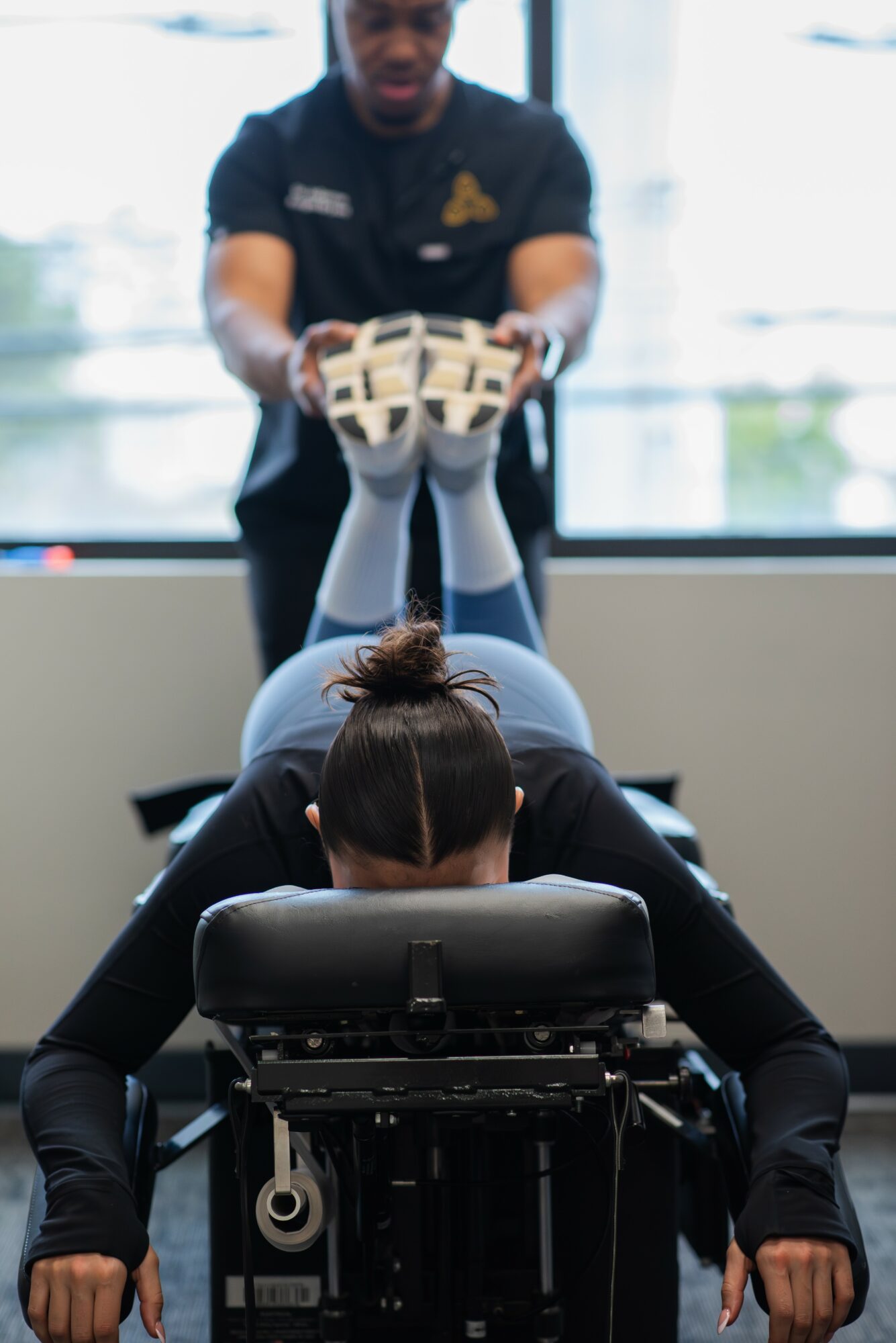 Physical therapist supports patient's legs during therapy session in a clinical setting.