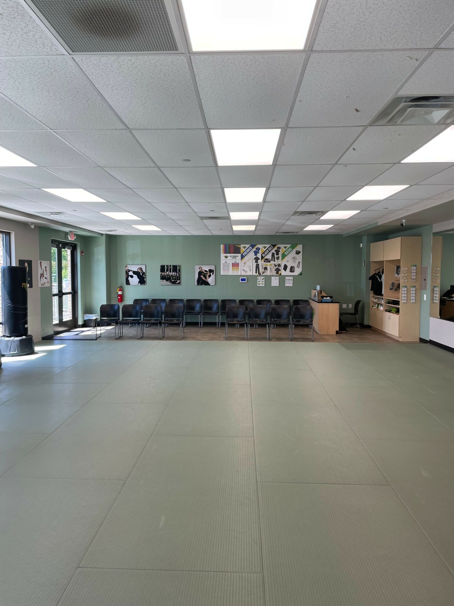 Empty room with chairs along the back wall, bulletin boards, and a door with glass panels on the left.