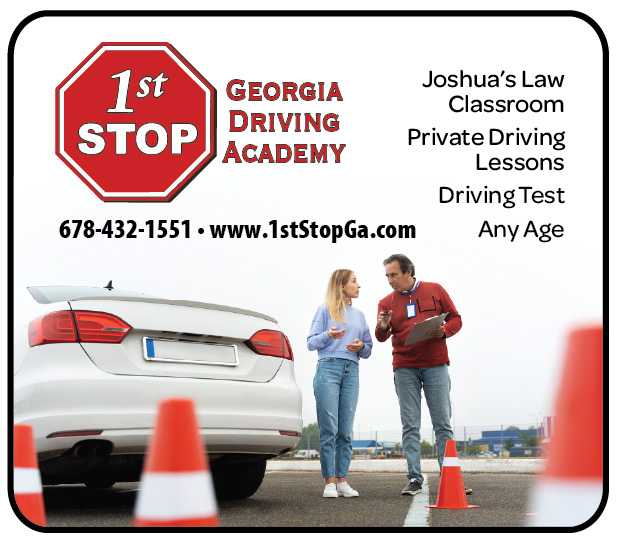 Two people talking near a white car with traffic cones in the foreground, at a driving school location.