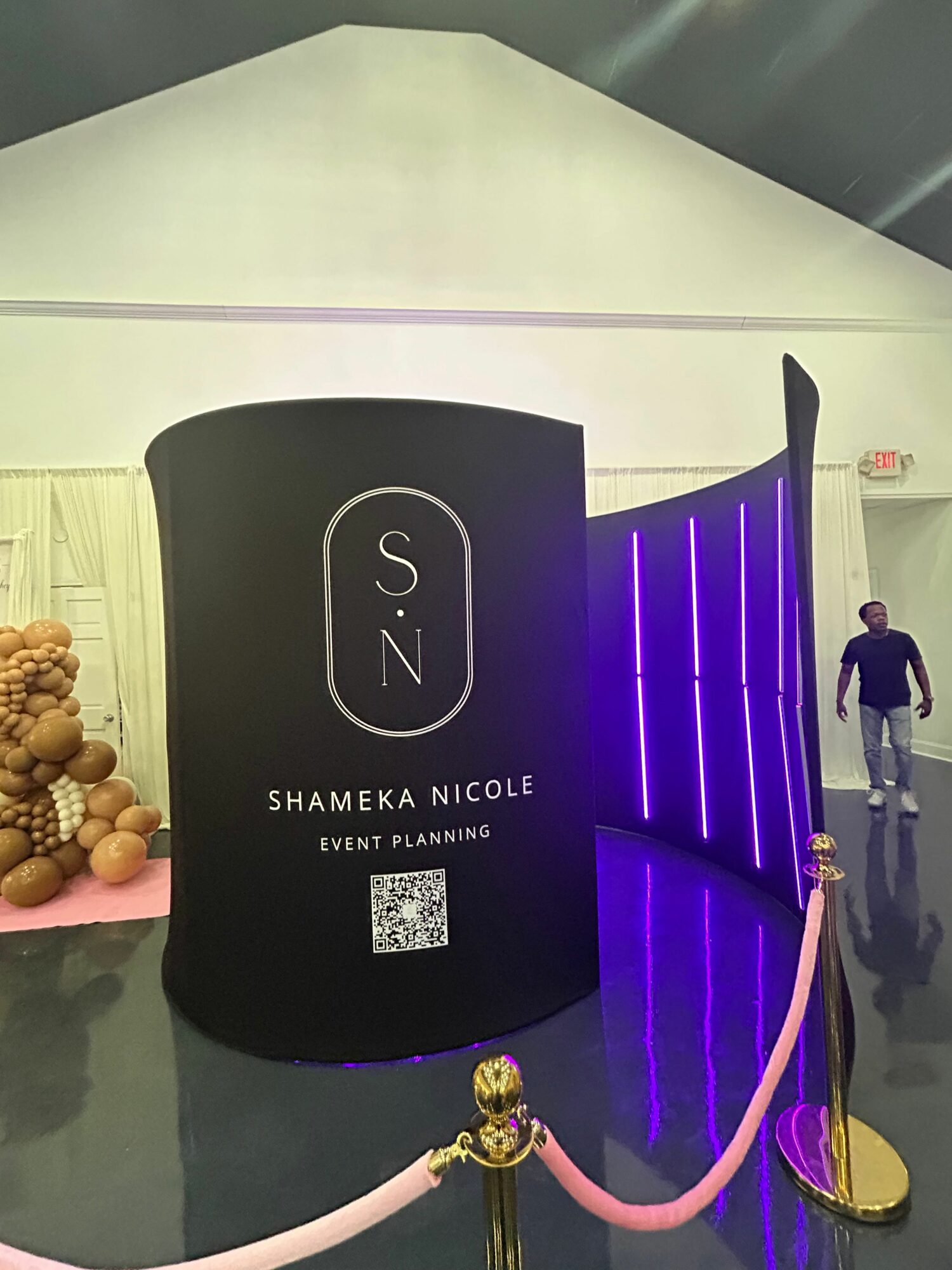 Large black display with white text and purple lighting, reading 'Shameka Nicole Event Planning,' inside a spacious venue.