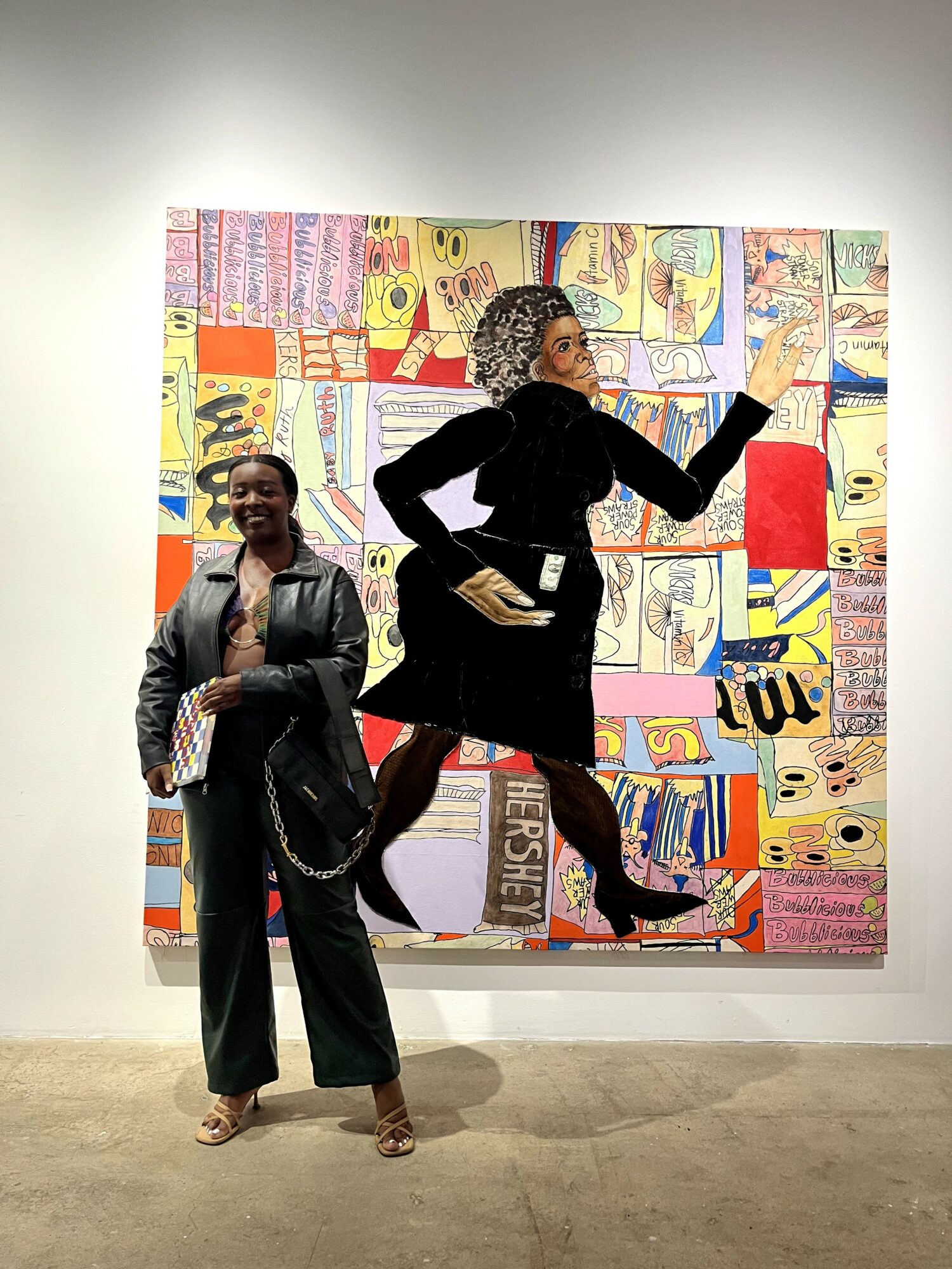 Two women standing in front of colorful abstract artwork, one smiling and the other pointing at the art.