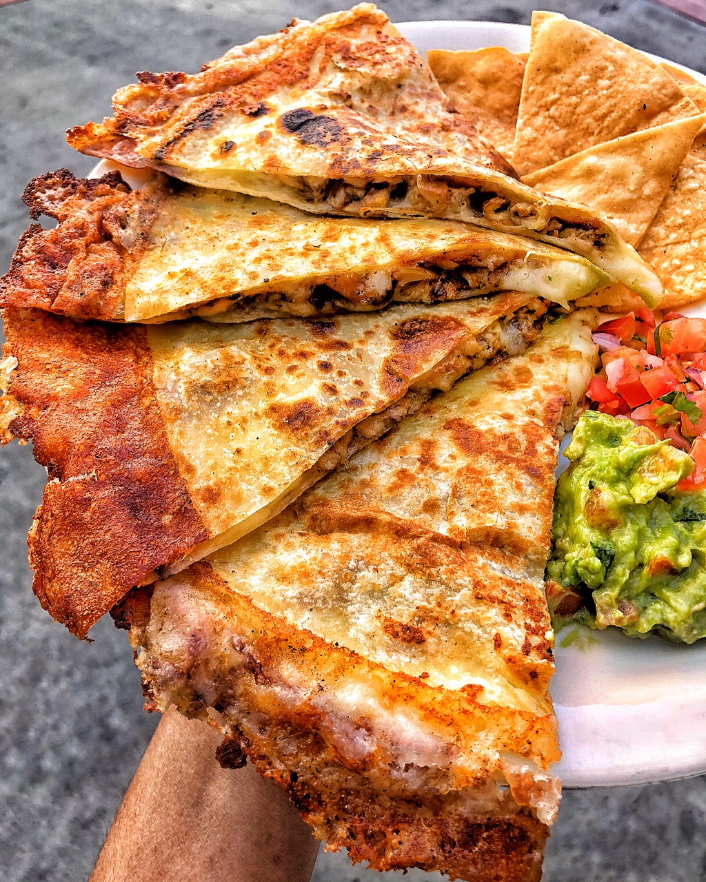 Plate with three slices of quesadilla, guacamole, and salsa on the side.