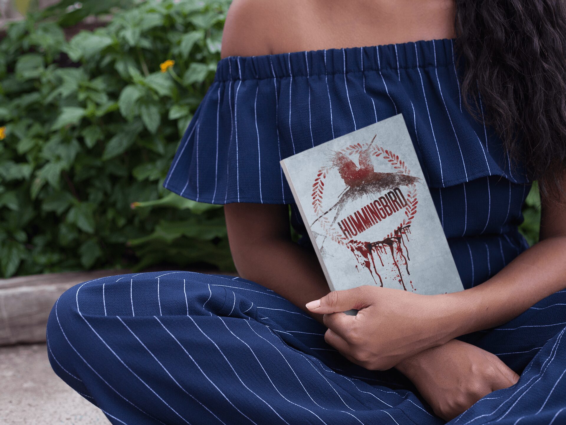 Person in off-shoulder striped dress holding a book with a lobster illustration and the word 'HUMANOID' on cover.