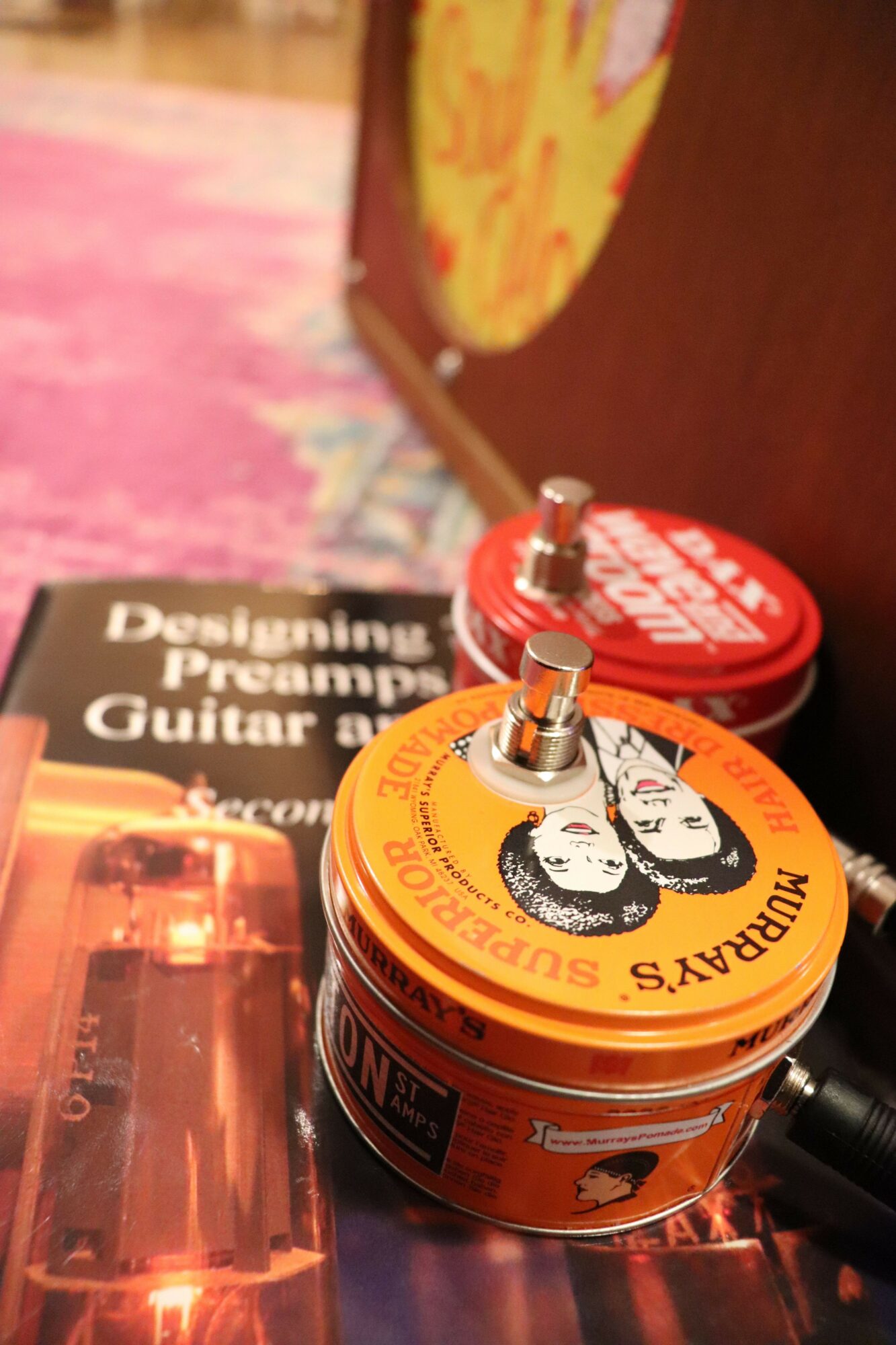 Two orange guitar effect pedals with black and white illustrations and text, placed on a wooden surface.