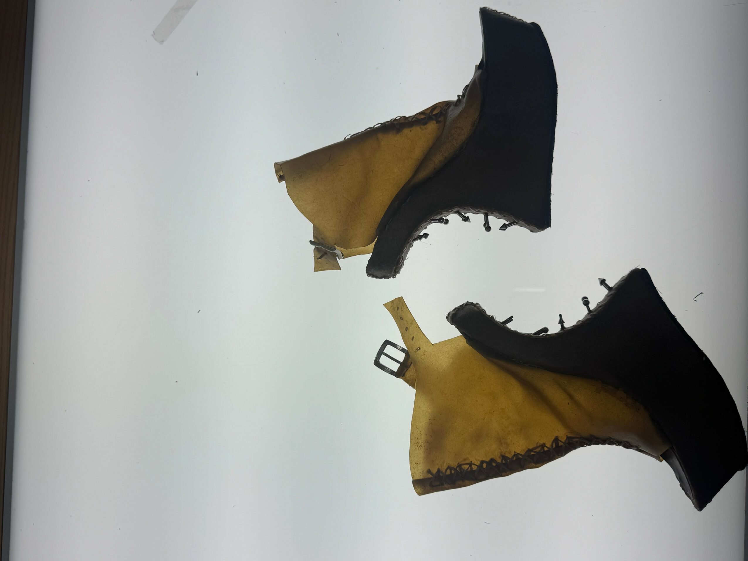 Pair of yellow and black shoes with worn soles, placed on a white surface.