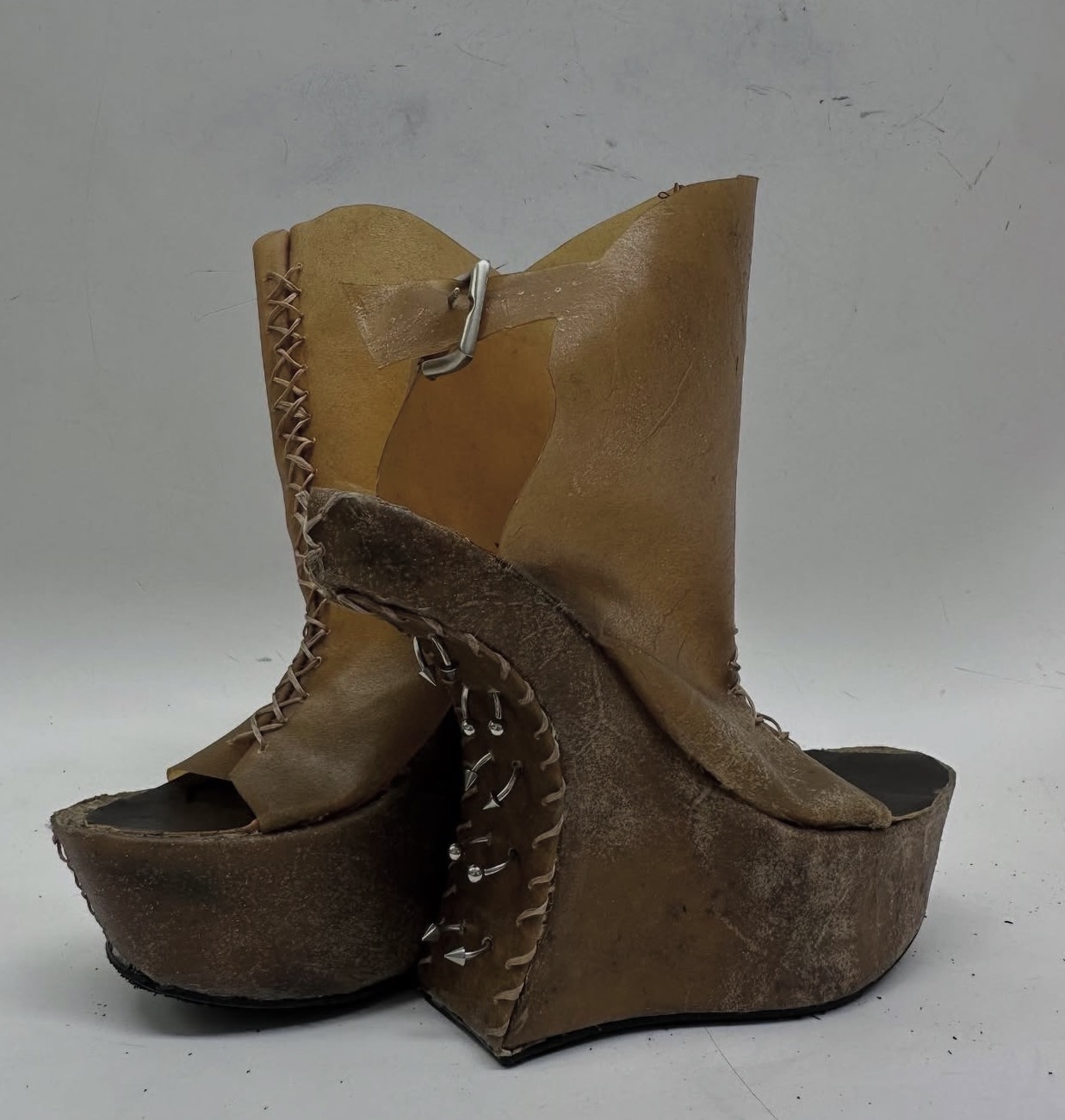 Pair of worn leather platform shoes with high heels and open toes, showing visible stitching and scuffs.