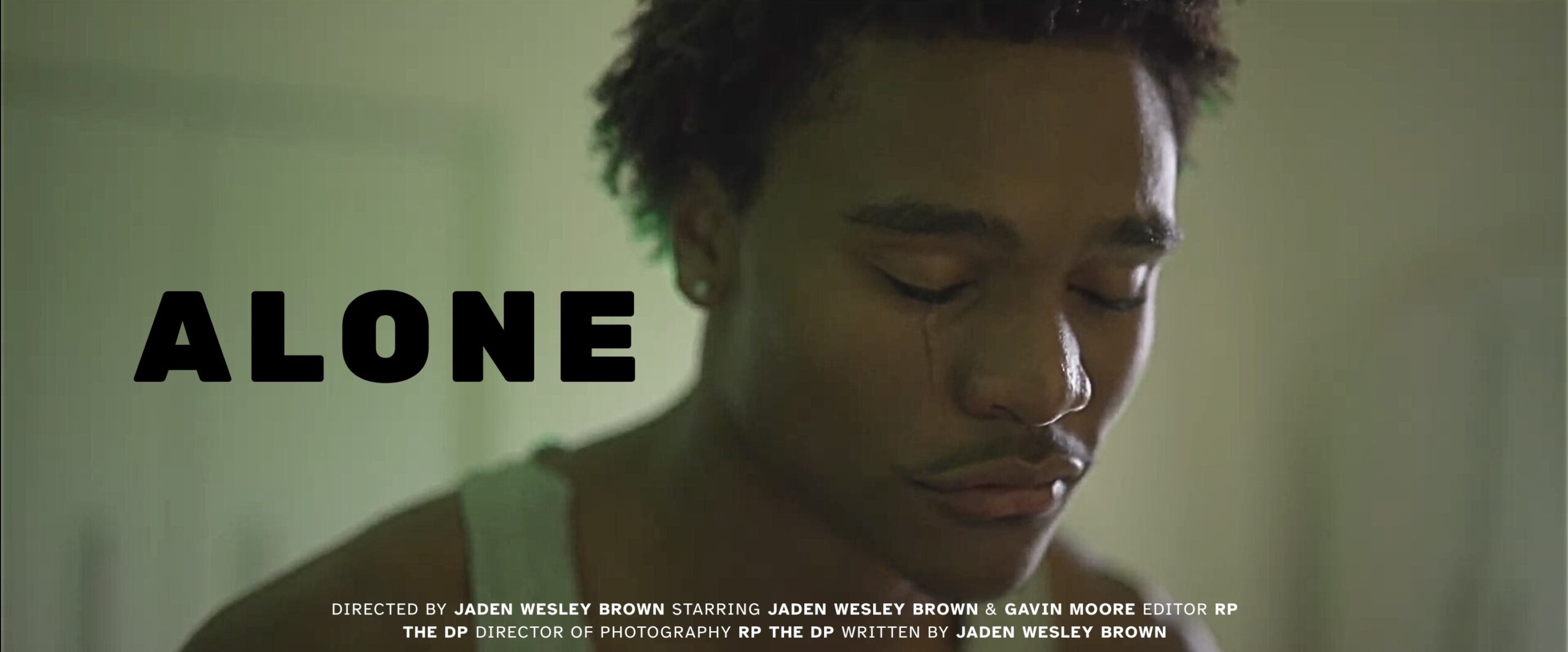 Close-up of a person with closed eyes, dark hair, and a neutral expression, with the word 'ALONE' in bold black letters.