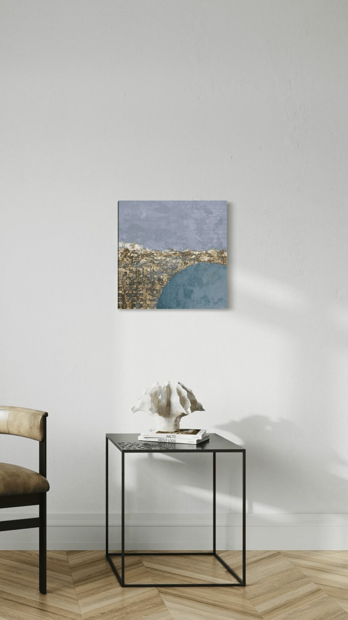 Small landscape painting on white wall above a glass table with a decorative object, next to a chair.