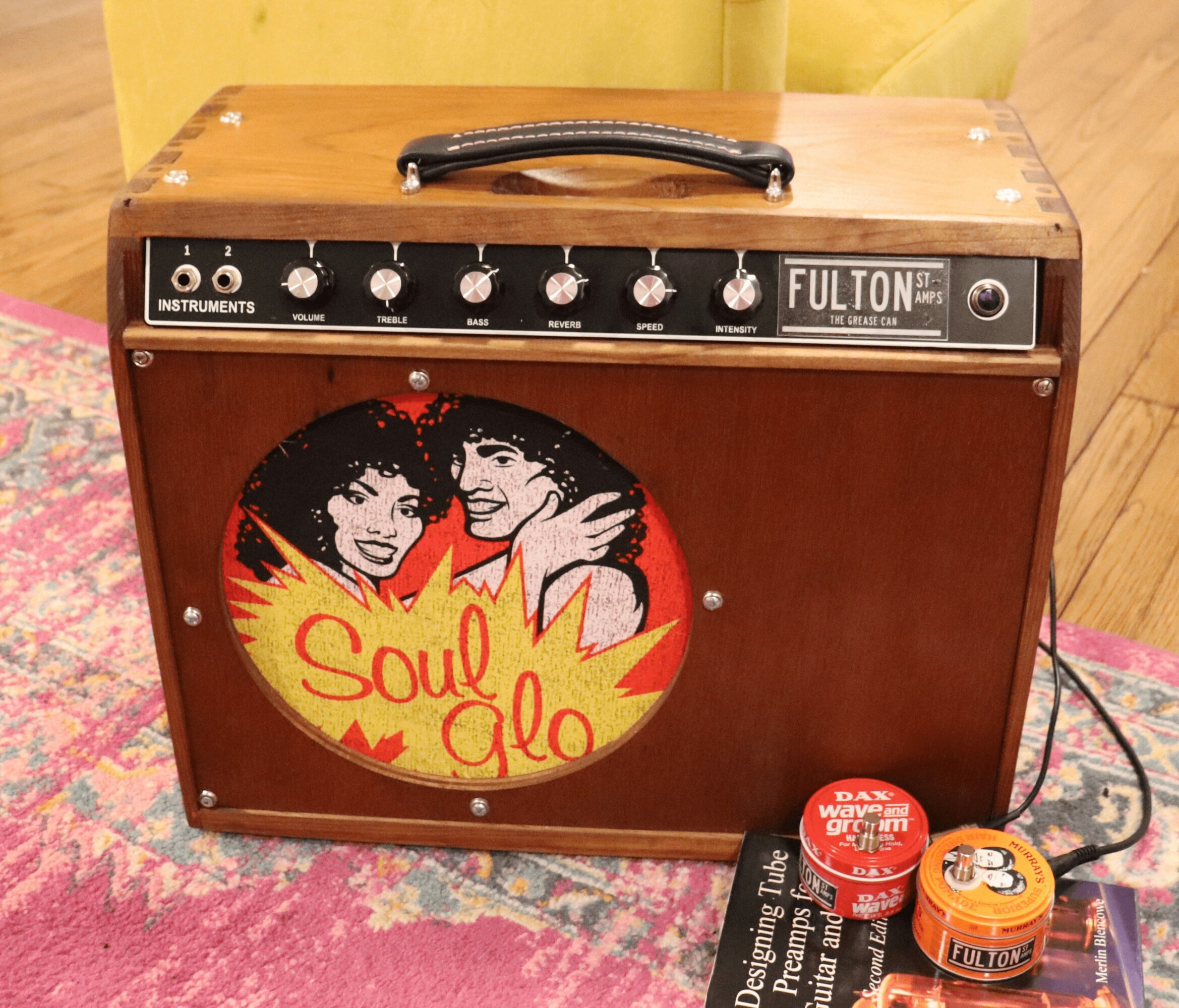 Wooden amplifier with a black control panel, a handle on top, and a colorful Soul & Glo sticker on the front.