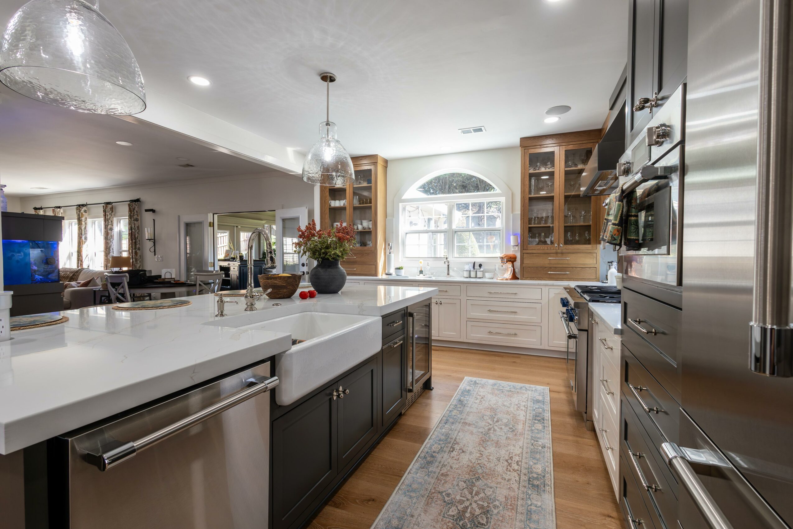 Modern kitchen with white countertops, dark cabinets, stainless steel appliances, and a window with a view.