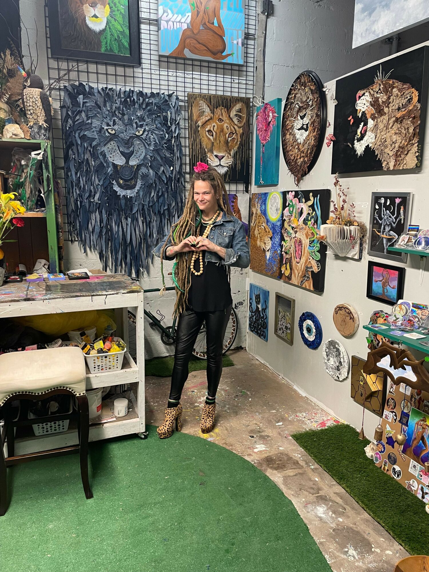 Young woman standing in art gallery surrounded by animal paintings and artwork on walls.