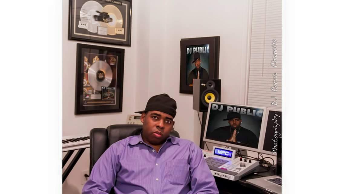 Young man in purple shirt sitting in a room with music awards and DJ equipment.