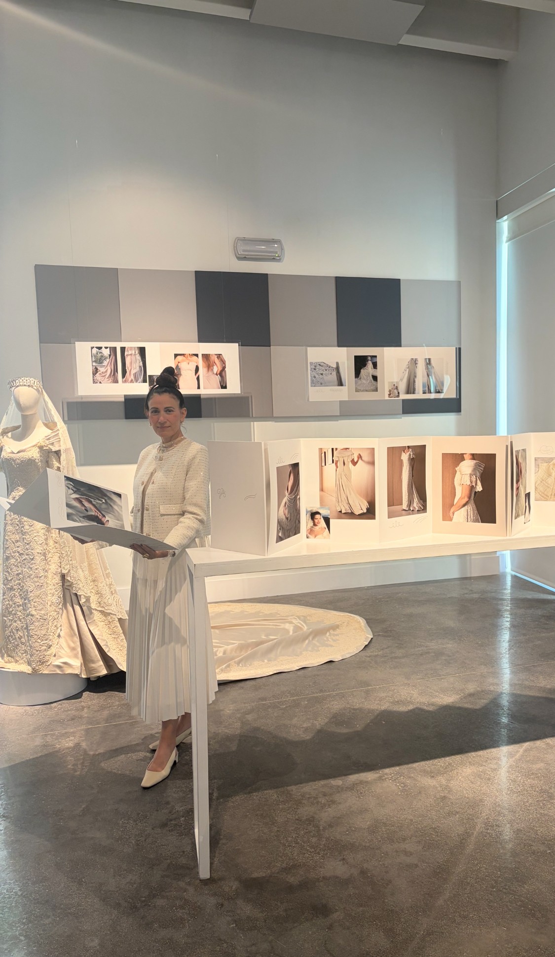 Person standing in an art gallery with display shelves and artwork in the background.