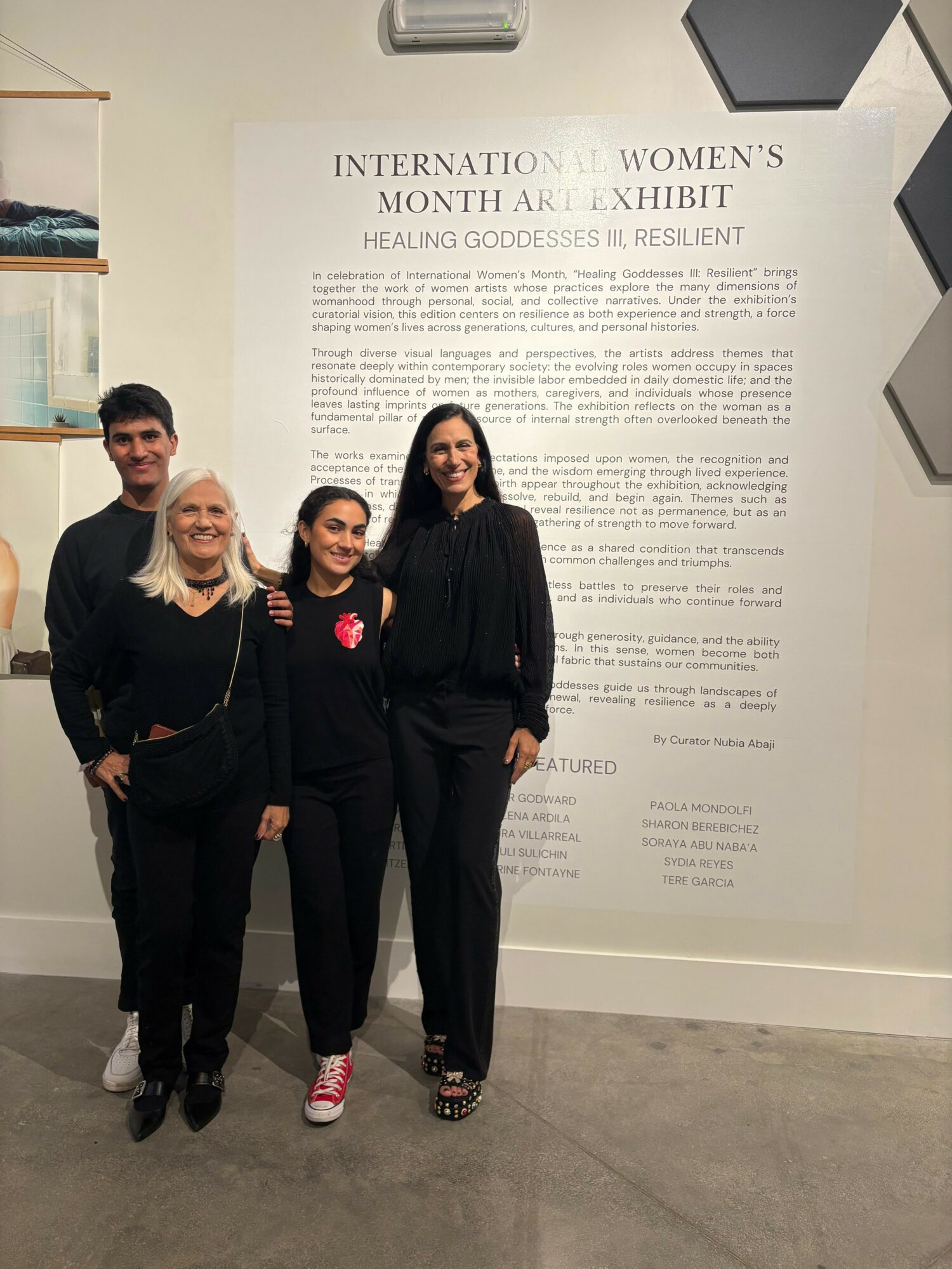 Four people standing in front of a large informational poster at an exhibit, smiling for the photo.