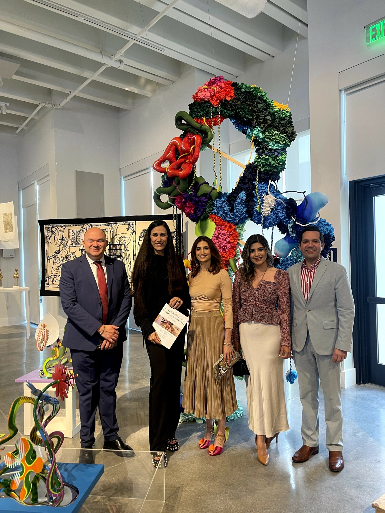 Five people standing indoors in front of colorful floral sculpture, smiling for the photo.