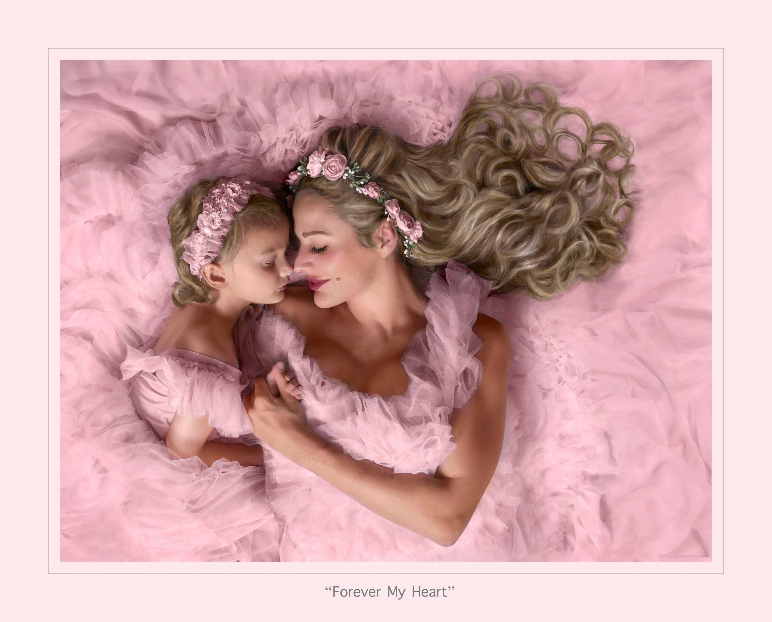 Woman and child lying on pink blanket, wearing matching pink dresses and floral headbands, touching foreheads.