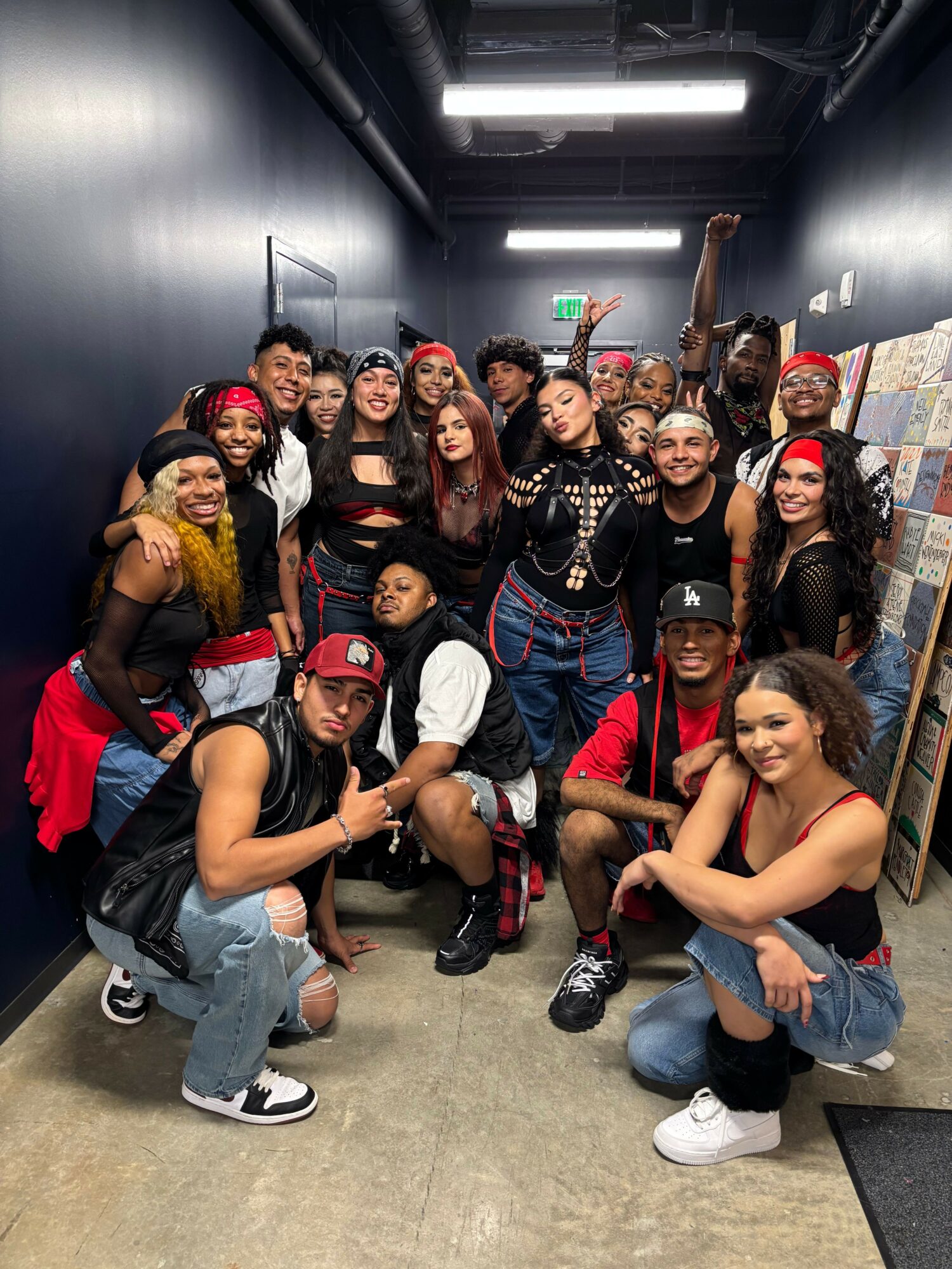 Group of diverse people in a hallway, some wearing red and black clothing, posing and smiling for the photo.