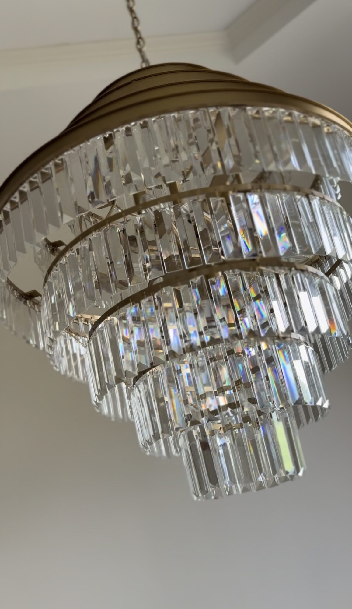 Chandelier with multiple tiers of hanging crystal prisms and a gold-colored frame.