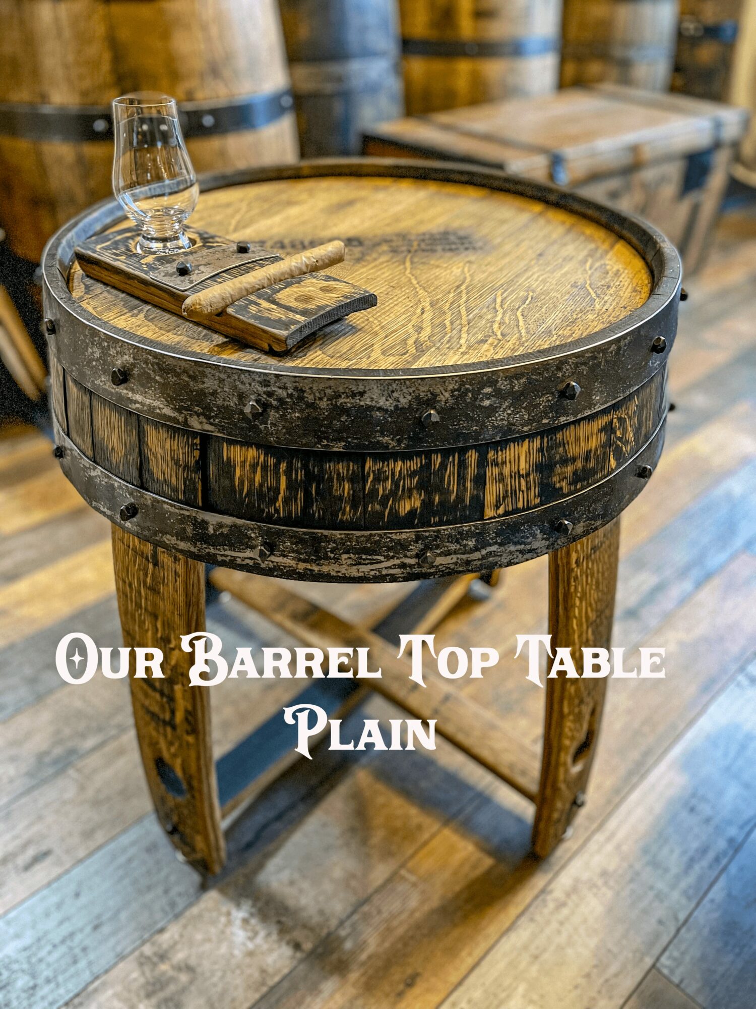 Round wooden barrel top table with metal bands, glass, and wooden tray on top, in a rustic setting.