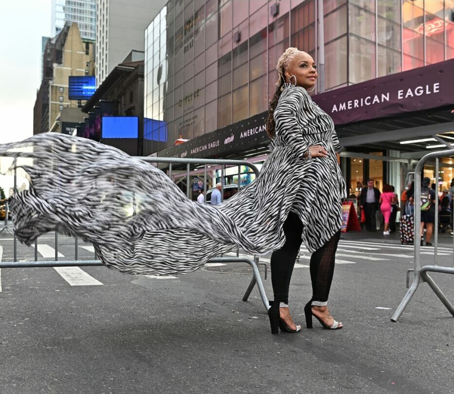 Person standing on city street with large eagle sculpture and buildings in background.