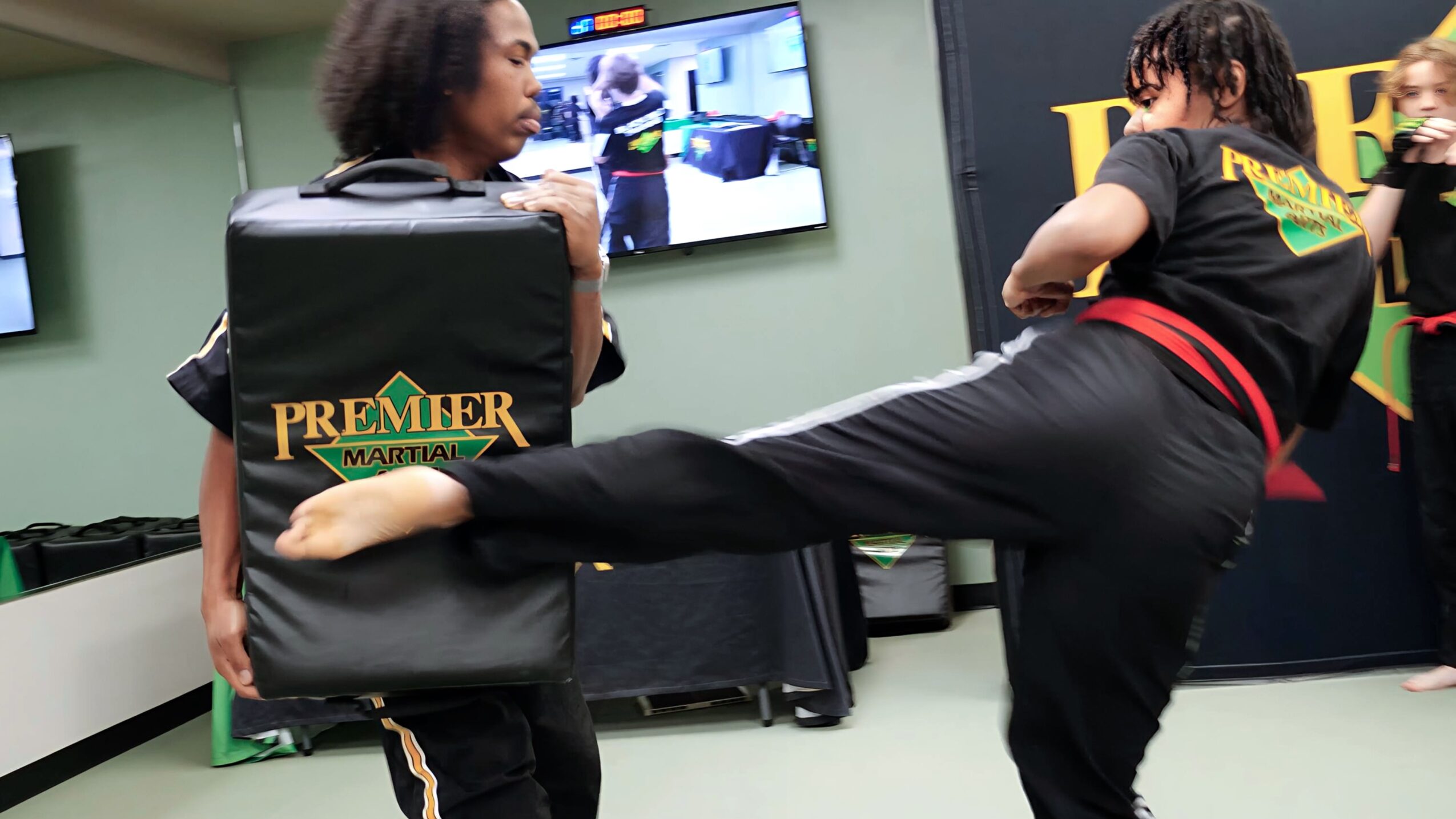 Two women practicing martial arts in a room with a television screen and equipment.