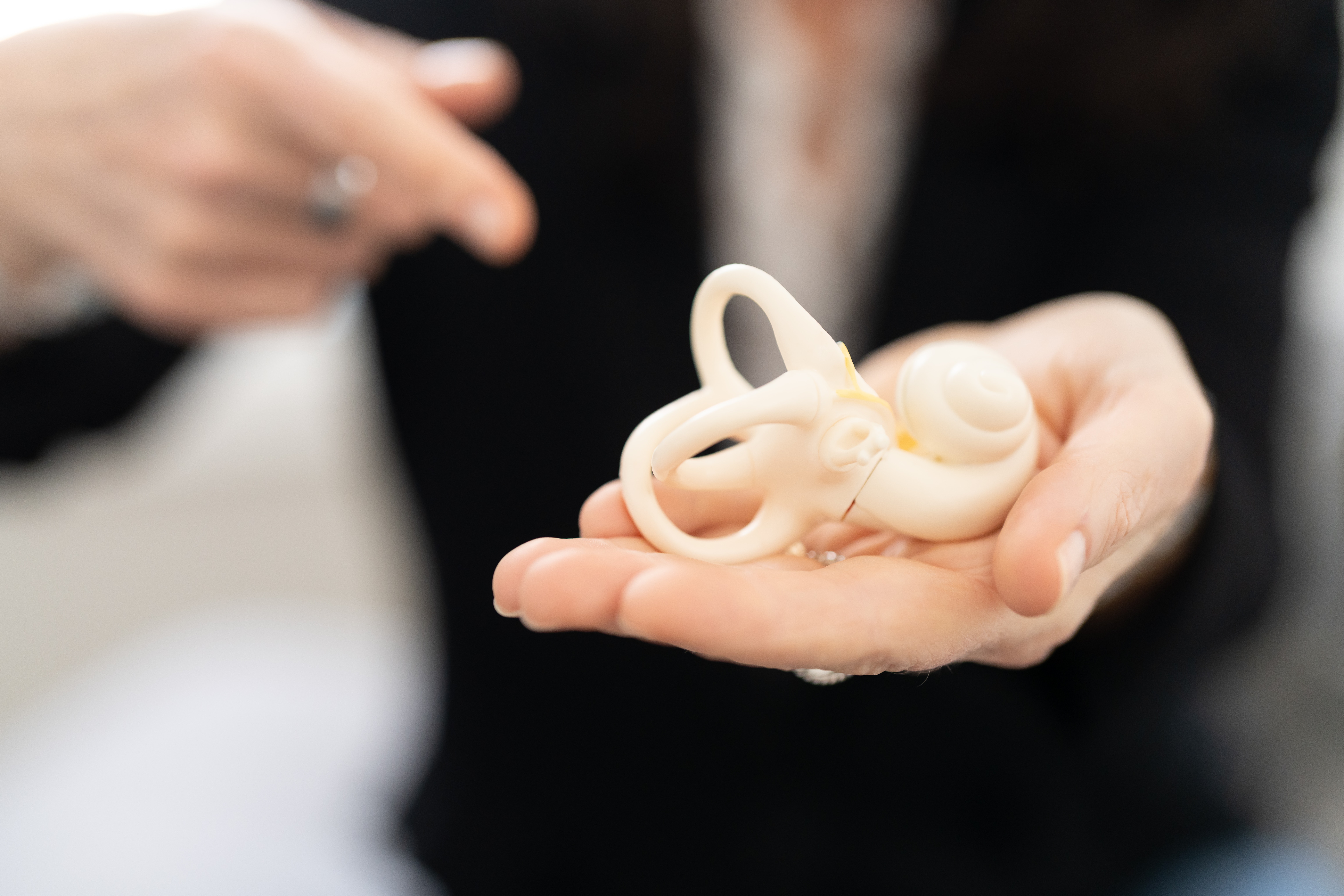 Person holding a small, cream-colored sculpture of an octopus in their hand, with another person in the background.
