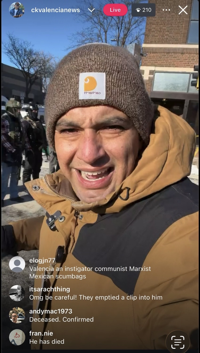 Man wearing a brown Carhartt beanie and yellow jacket outdoors, smiling at the camera.