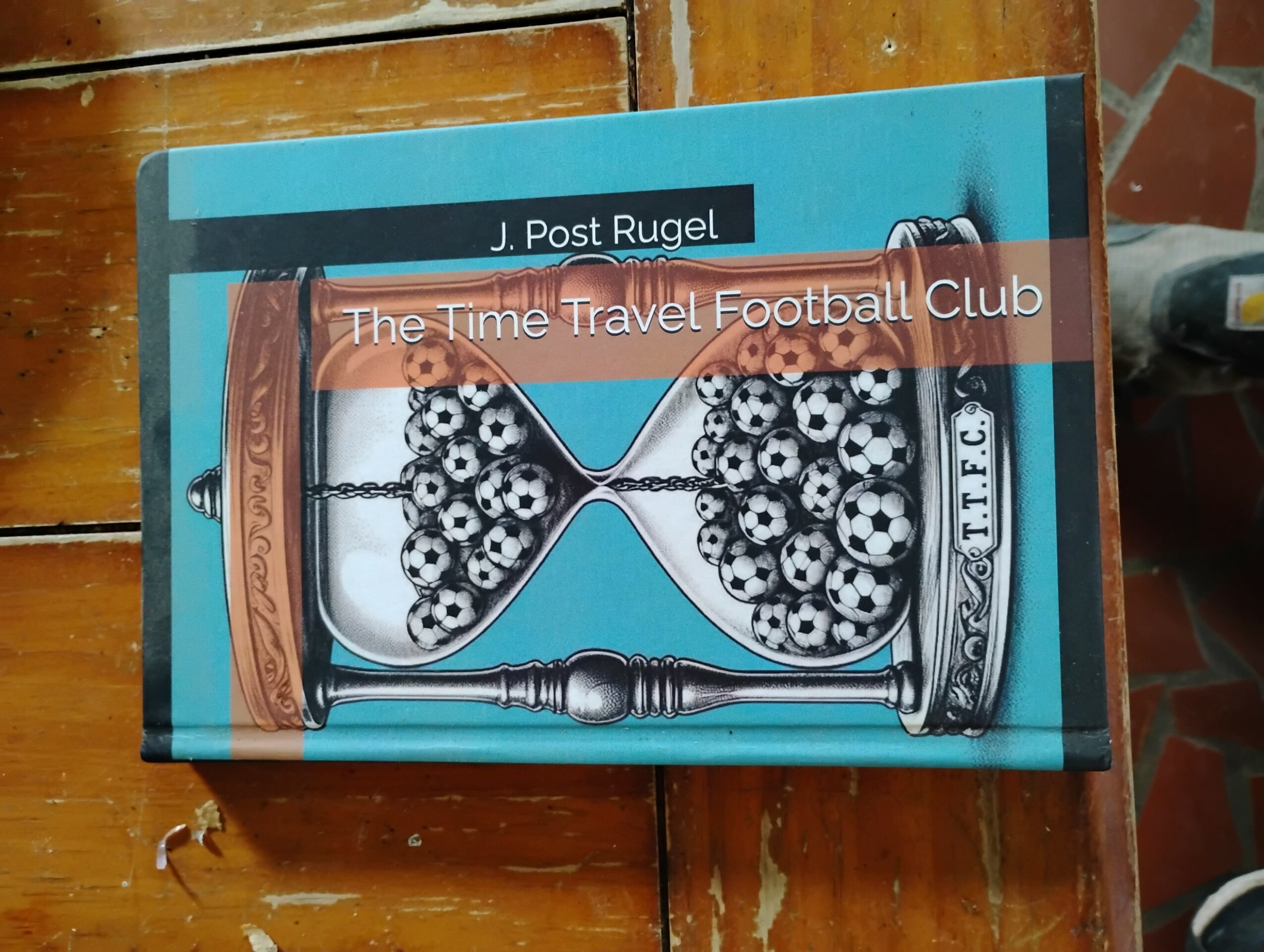 Book titled 'The Time Travel Football Club' by J. Post Rugel, with a blue cover and an illustration of a vintage cricket set.