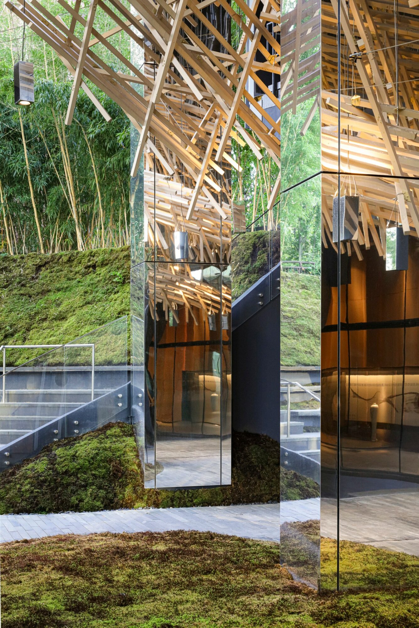 Multiple mirrors reflect a grassy outdoor area and a wooden ceiling structure with beams and lighting fixtures.