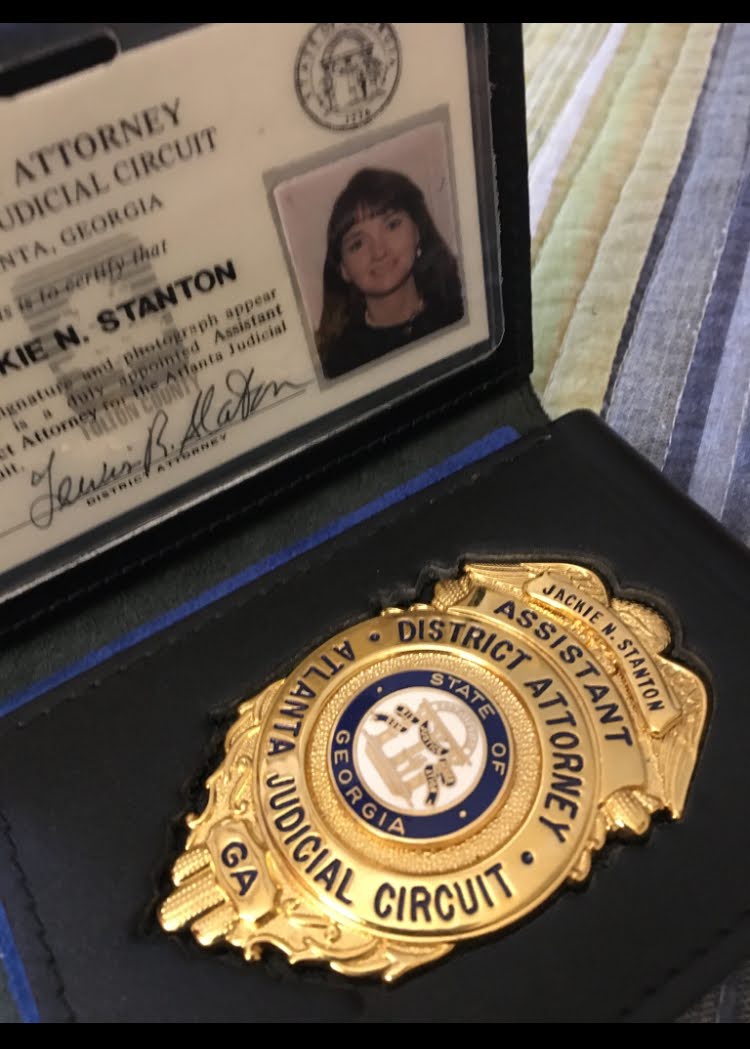 Judge's badge and identification card inside a case, with a striped fabric surface nearby.