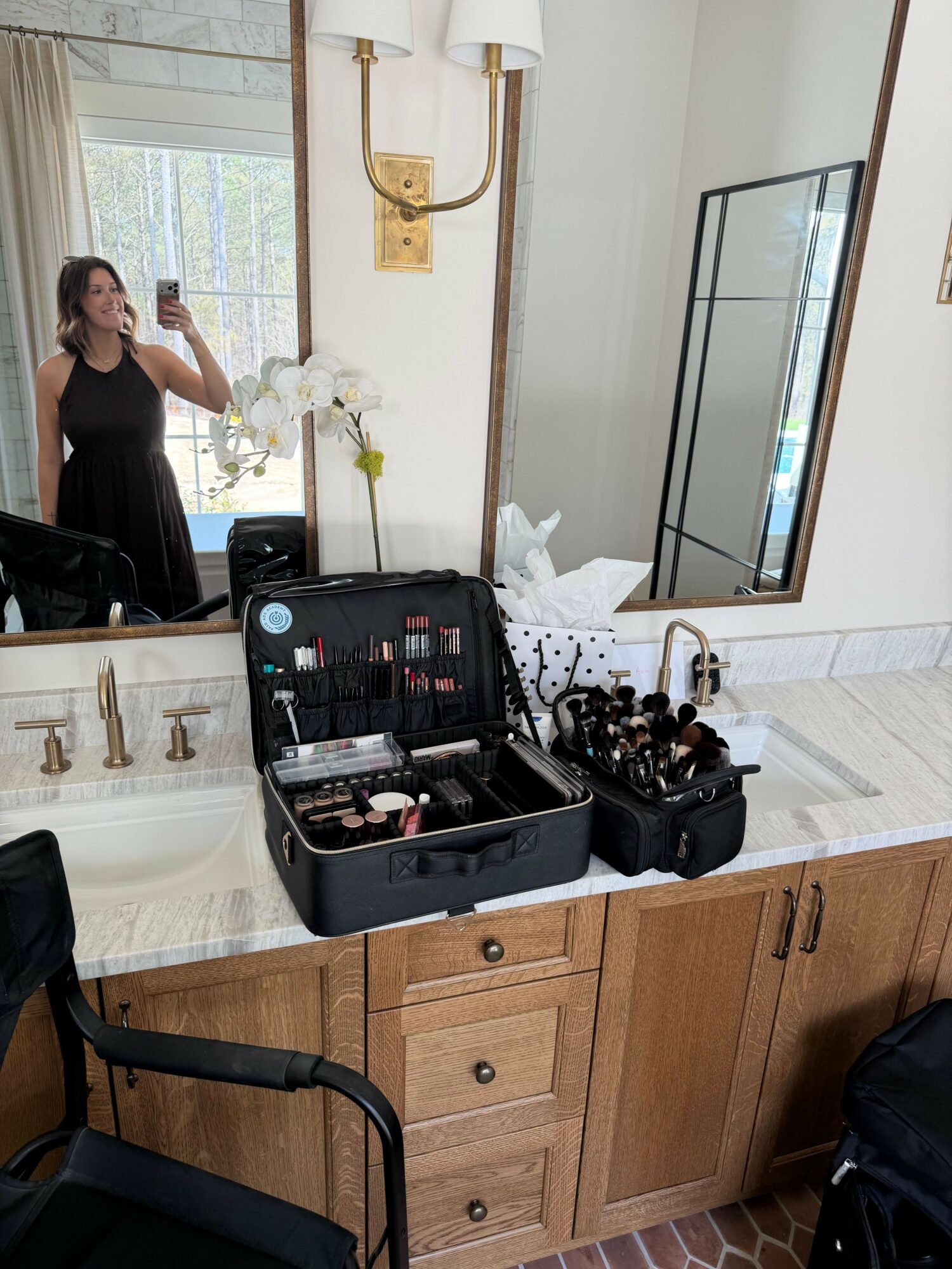 Makeup and beauty products on a table with a mirror, in a room with wooden cabinets and a window.