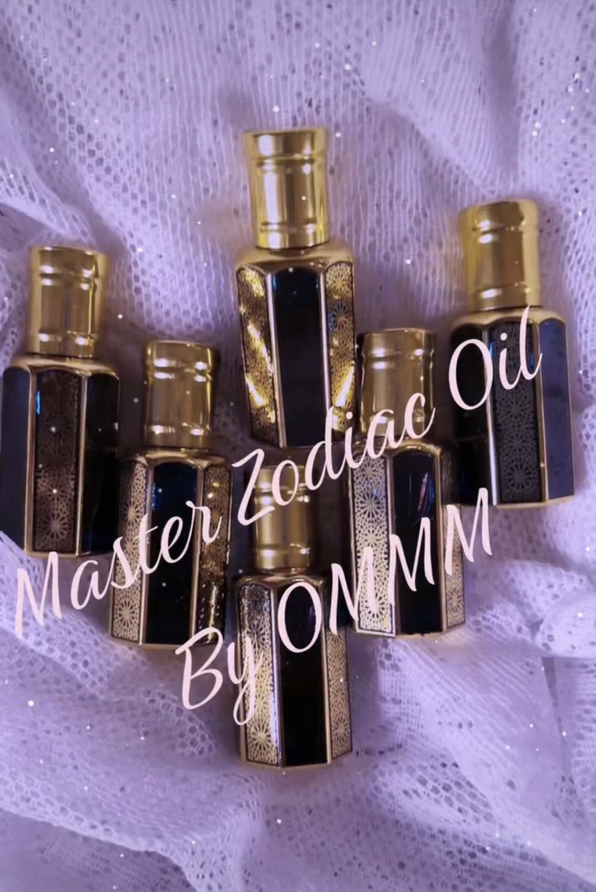 Five small perfume bottles with black and gold caps on purple fabric background.