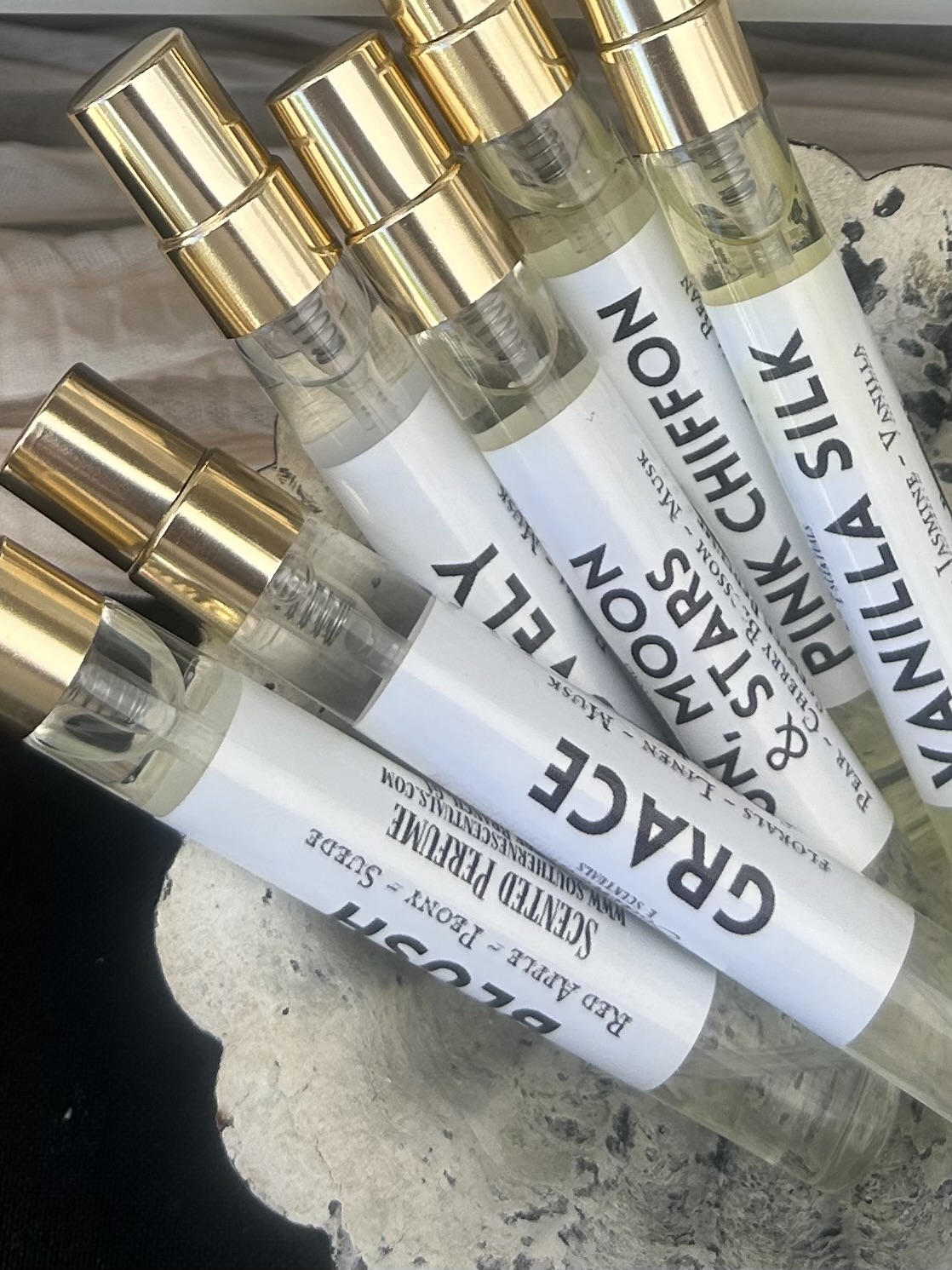Six clear spray bottles with gold caps labeled 'VANILLA CHIFFON' and 'VANILLA SILK' on a surface.
