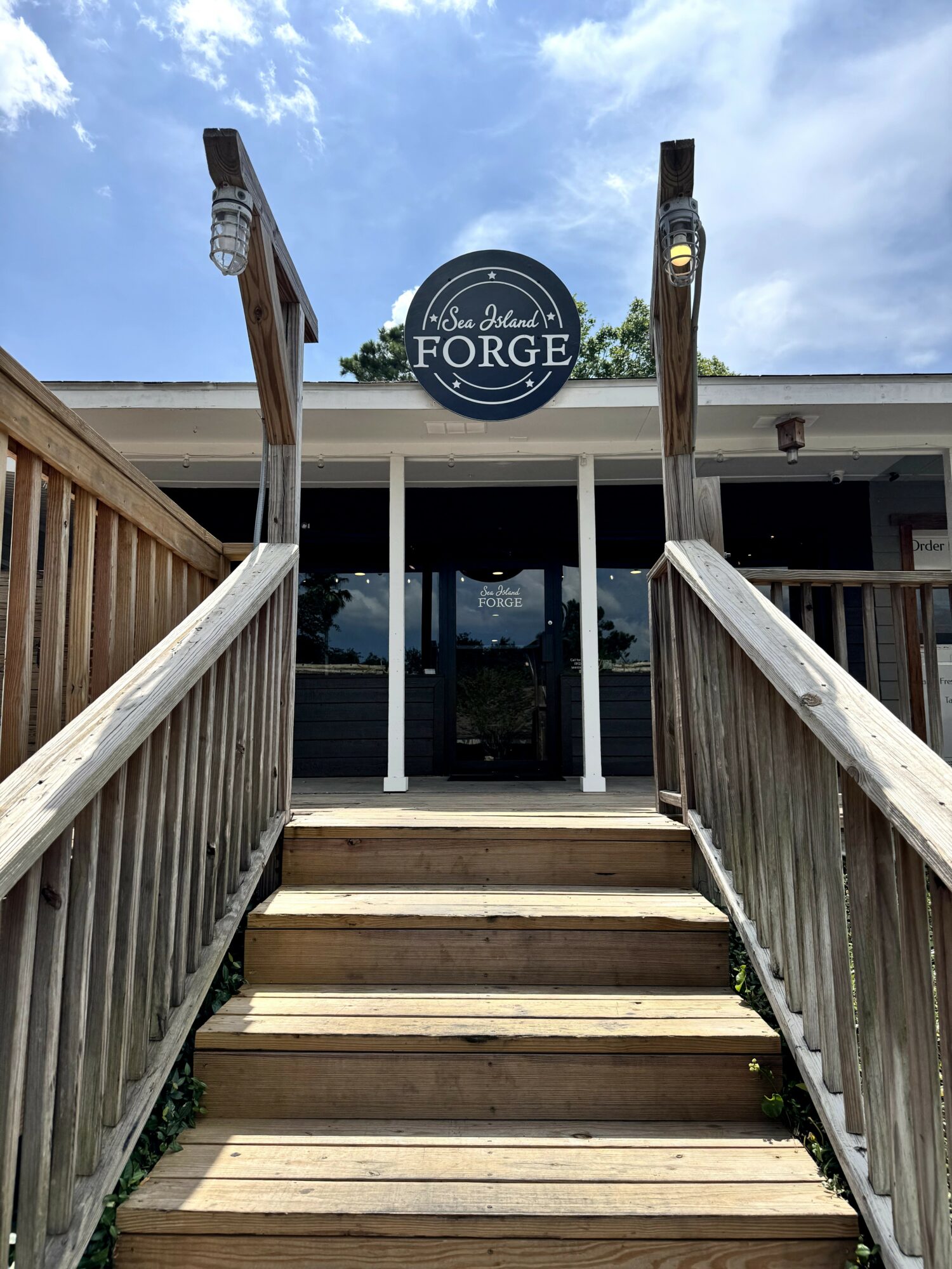 Wooden stairs leading to a building with a sign that reads 'The Forge' under a partly cloudy sky.