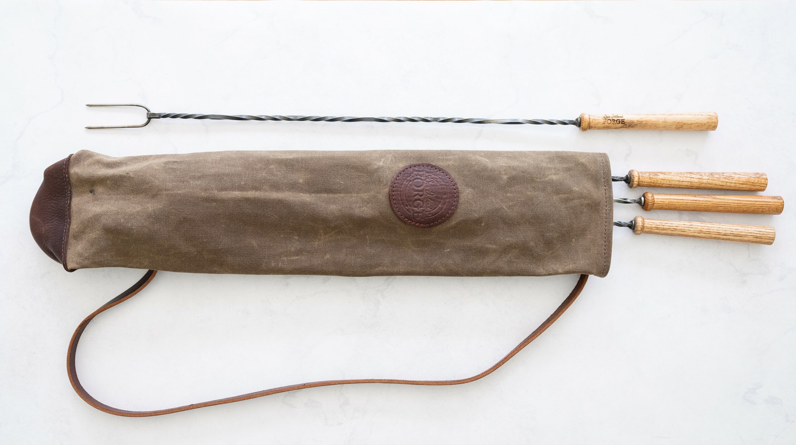 Barbecue tool set with a long metal skewer, three wooden-handled tools, and a carrying case, on a white background.